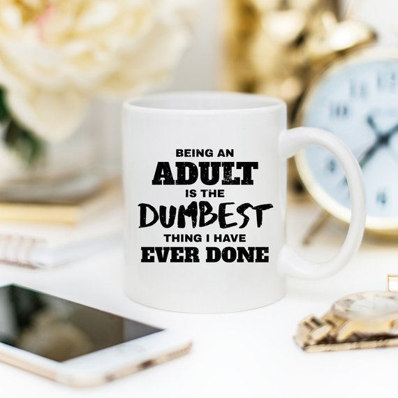 A humorous coffee mug with the phrase 'Being An Adult Is The Dumbest Thing I Have Ever Done' printed on it, showcasing a fun design.