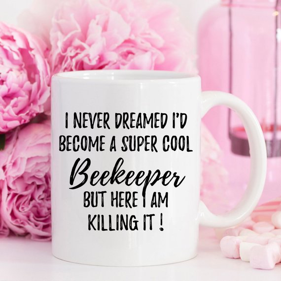 A white ceramic Beekeeper Mug featuring a vibrant bee design printed on both sides, perfect for coffee or tea.