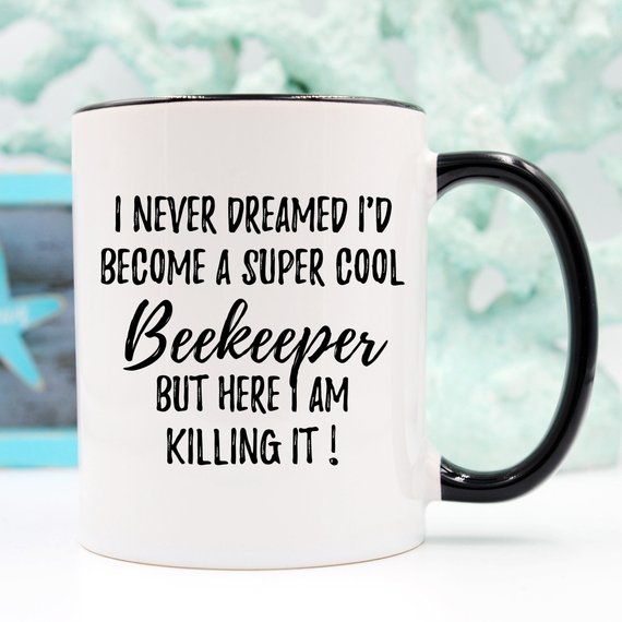 A white ceramic Beekeeper Mug featuring a vibrant bee design printed on both sides, perfect for coffee or tea.