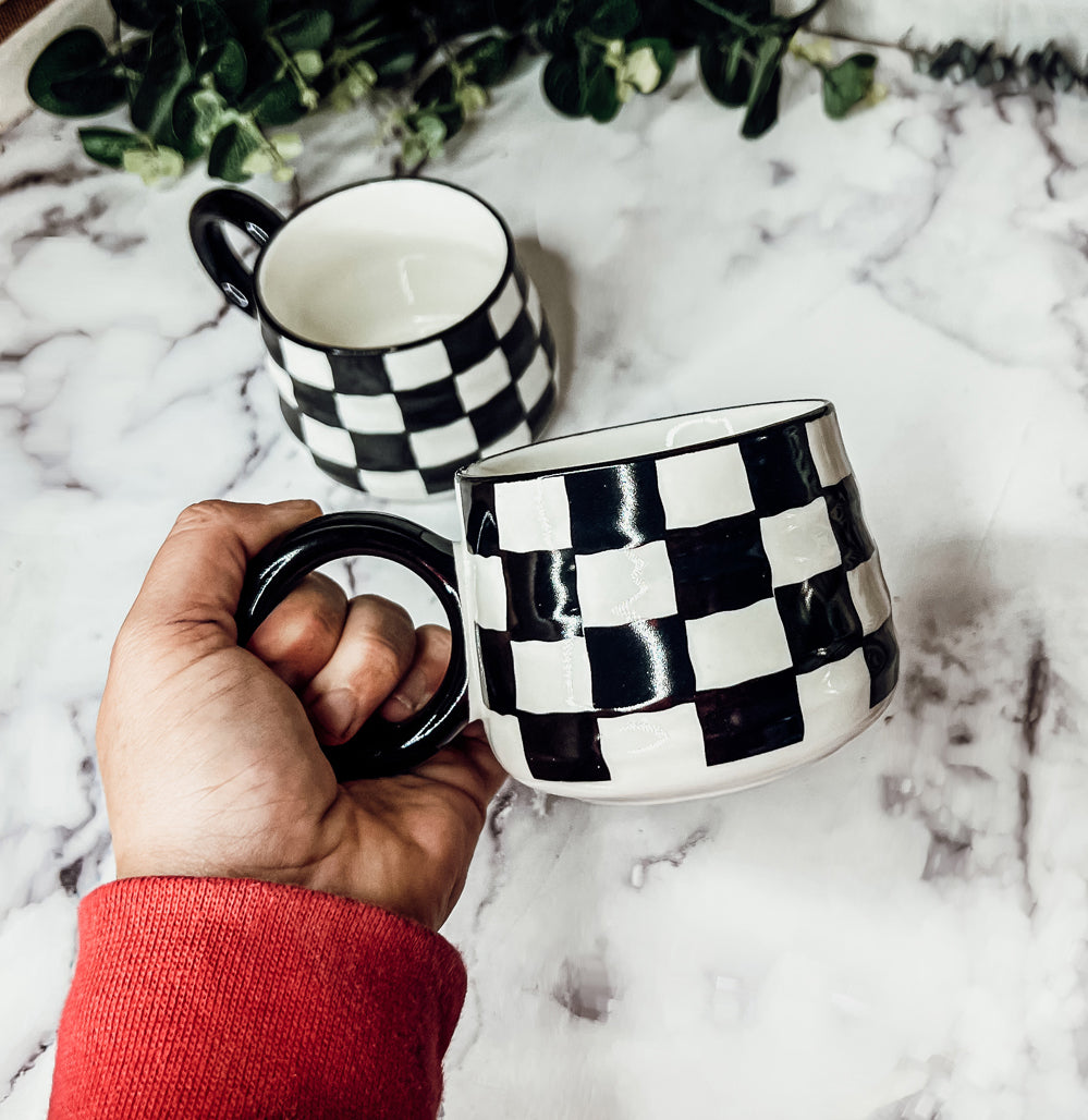 A stylish BW Checkered Mug featuring a hand-painted black and white checkered design, perfect for coffee, tea, or hot chocolate.