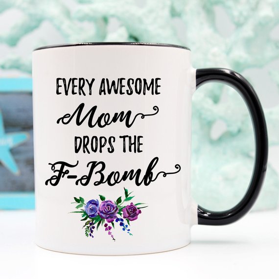 A white ceramic mug with the phrase 'Every Awesome Mom Drops the F Bomb' printed in vibrant colors on both sides, perfect for coffee lovers.
