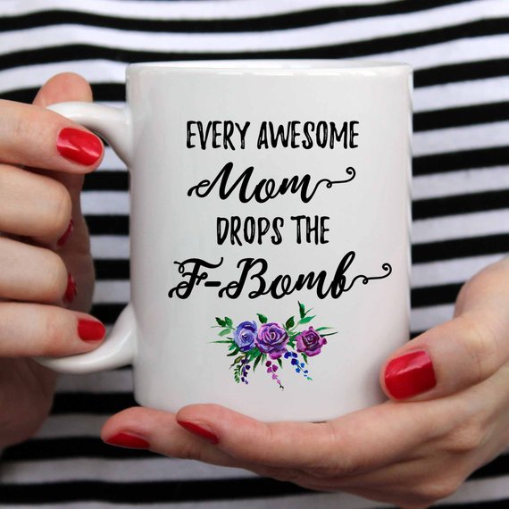 A white ceramic mug with the phrase 'Every Awesome Mom Drops the F Bomb' printed in vibrant colors on both sides, perfect for coffee lovers.