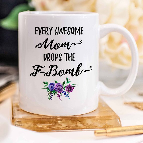A white ceramic mug with the phrase 'Every Awesome Mom Drops the F Bomb' printed in vibrant colors on both sides, perfect for coffee lovers.