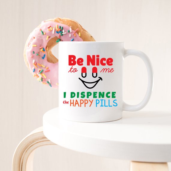 Funny Nurse Mug featuring the phrase 'Be Nice To Me, I Dispence The Happy Pills', designed for nurses with a humorous touch.