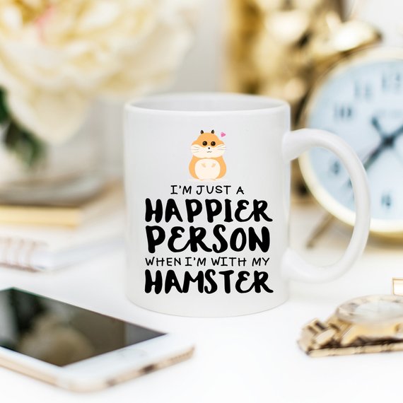 A humorous coffee mug featuring a hamster design with the text 'I'm Just A Happier Person When I'm With My Hamster', made of high-quality ceramic.