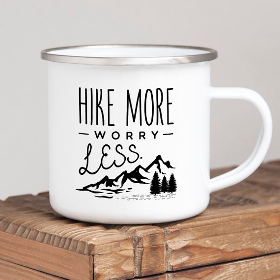 A white enamel mug with a stainless steel rim, featuring a vibrant wanderlust design printed on both sides, perfect for hiking and outdoor adventures.