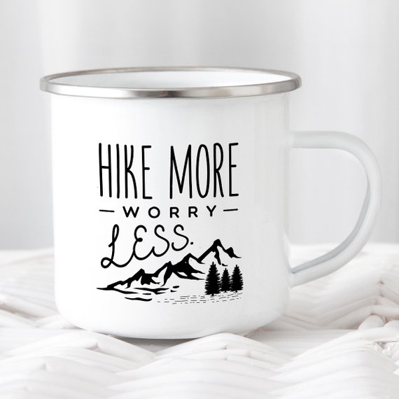 A white enamel mug with a stainless steel rim, featuring a vibrant wanderlust design printed on both sides, perfect for hiking and outdoor adventures.