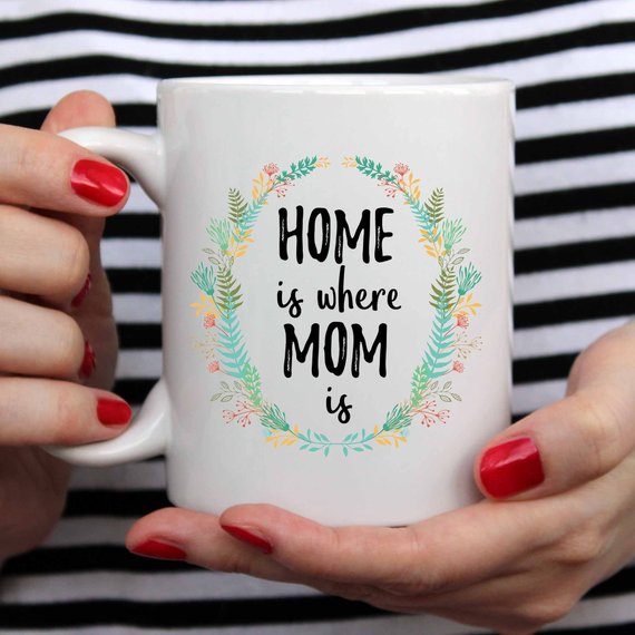 A white ceramic mug with the phrase 'Home Is Where Mom Is' printed in vibrant colors on both sides, showcasing a heartfelt design.