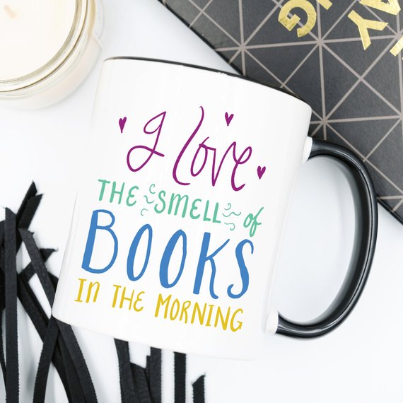 A humorous coffee mug featuring the phrase 'I Love The Smell Of Books In The Morning', designed for book lovers and coffee enthusiasts.
