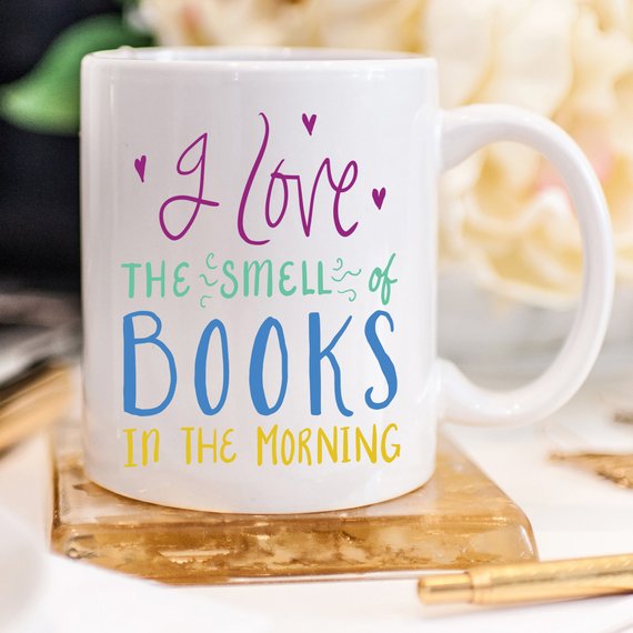 A humorous coffee mug featuring the phrase 'I Love The Smell Of Books In The Morning', designed for book lovers and coffee enthusiasts.