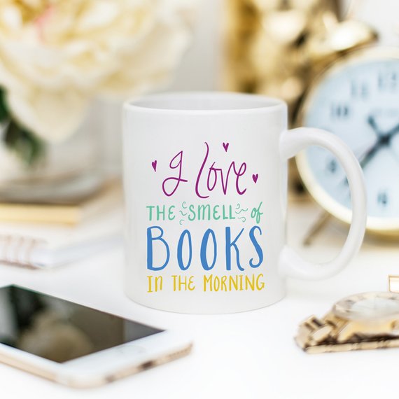 A humorous coffee mug featuring the phrase 'I Love The Smell Of Books In The Morning', designed for book lovers and coffee enthusiasts.