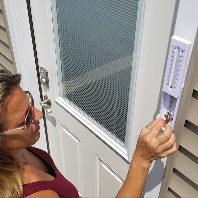 A Secret Safe Indoor/Outdoor Thermometer designed to hide valuables, featuring a slide open compartment and dual hanging slots.