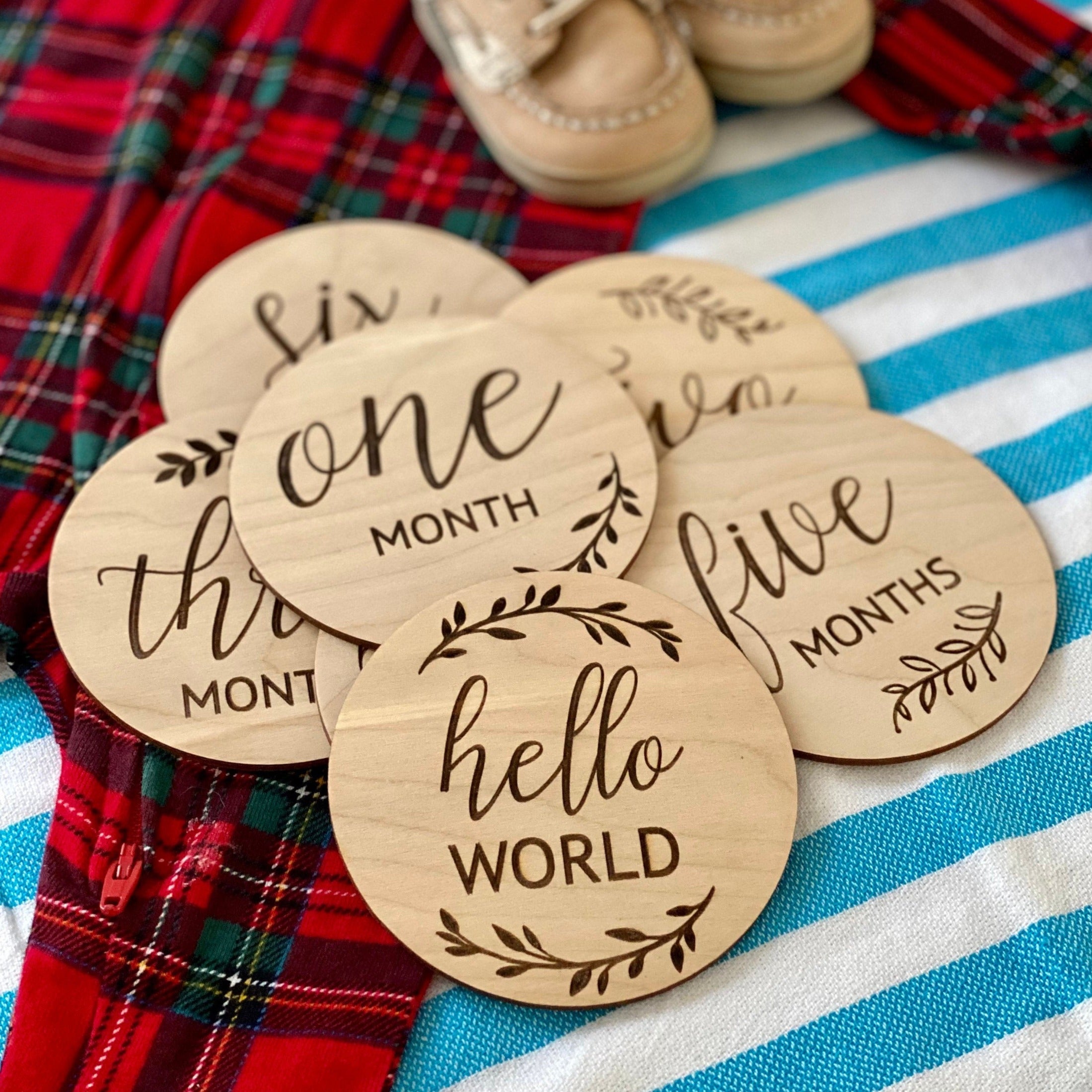 A set of 12 baby milestone wood cards, beautifully engraved on Birch wood discs, showcasing months from 1 to 12, displayed in a Kraft box.