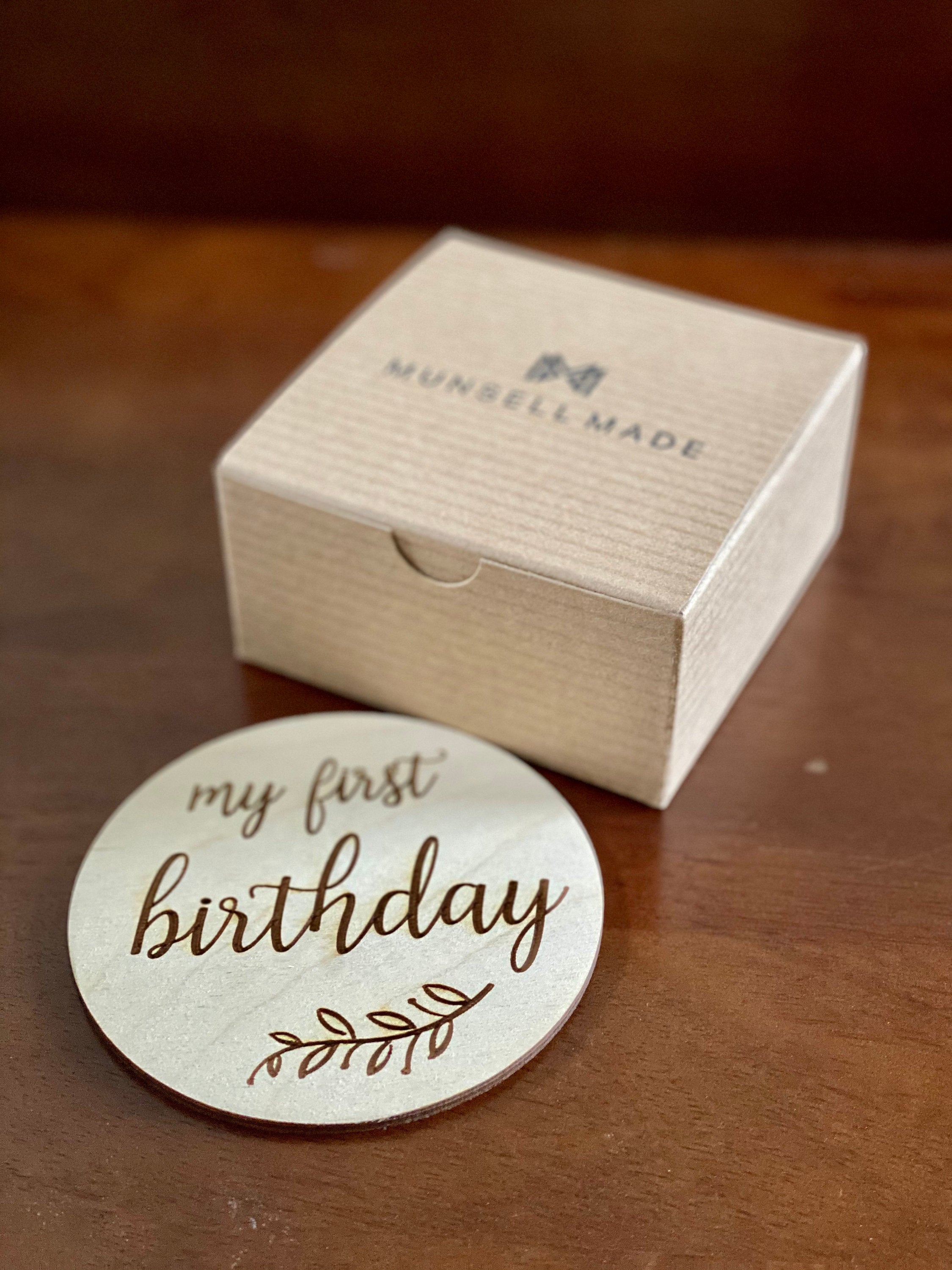 A set of beautifully crafted Birch wood milestone discs for baby's first holidays, featuring engraved text and a Kraft storage box.