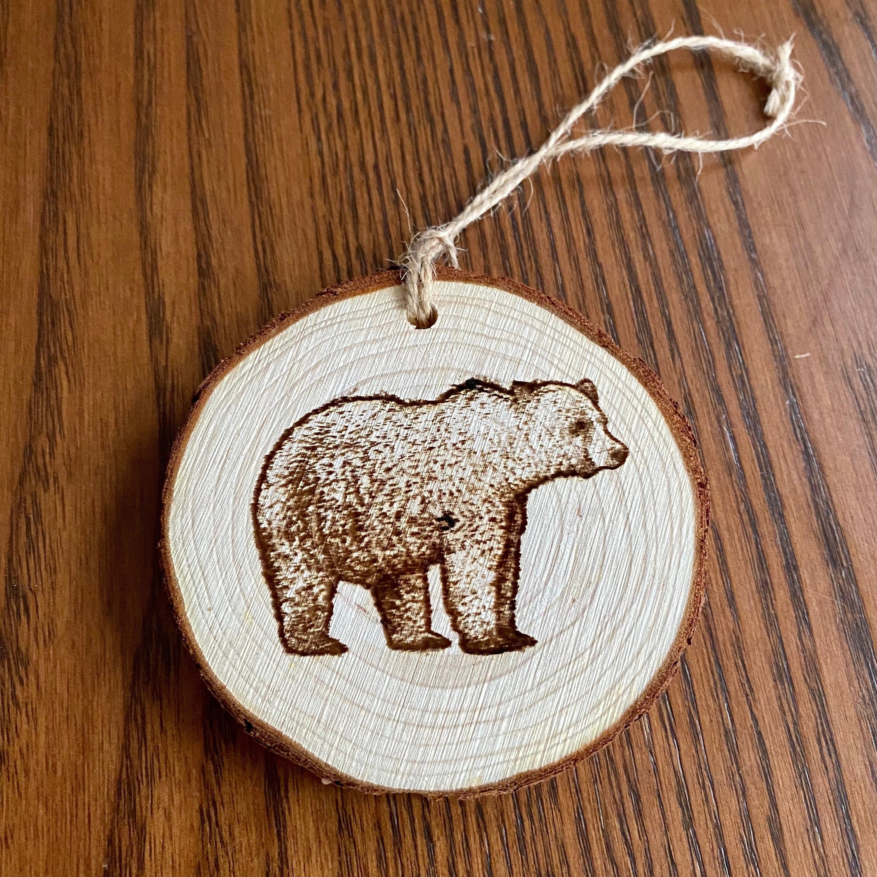 Rustic bear engraved wood slice Christmas ornament with twine, perfect for holiday decor.