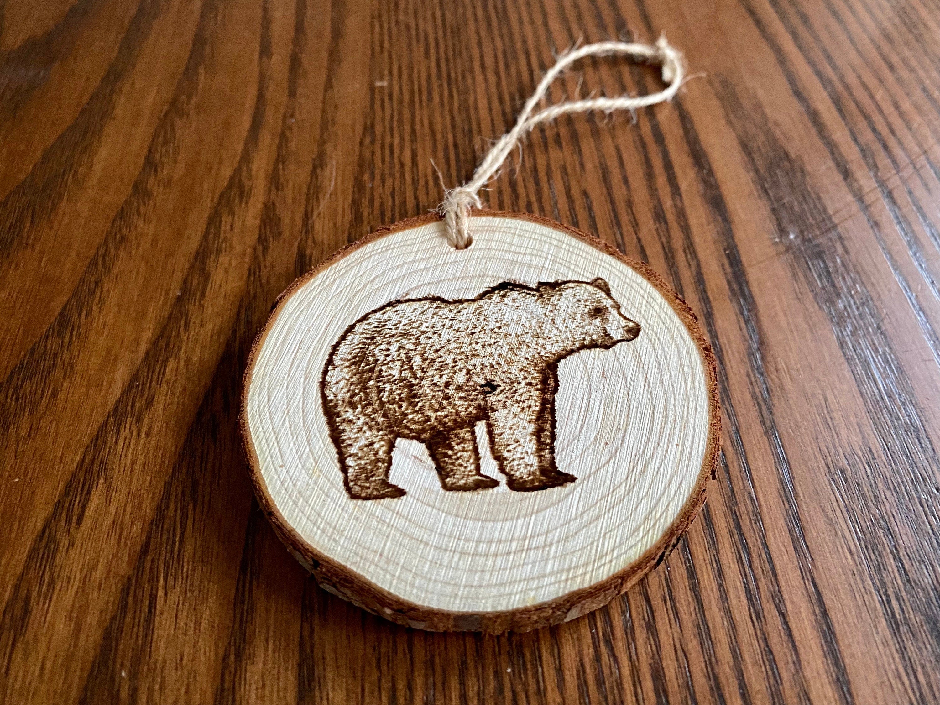Rustic bear engraved wood slice Christmas ornament with twine, perfect for holiday decor.