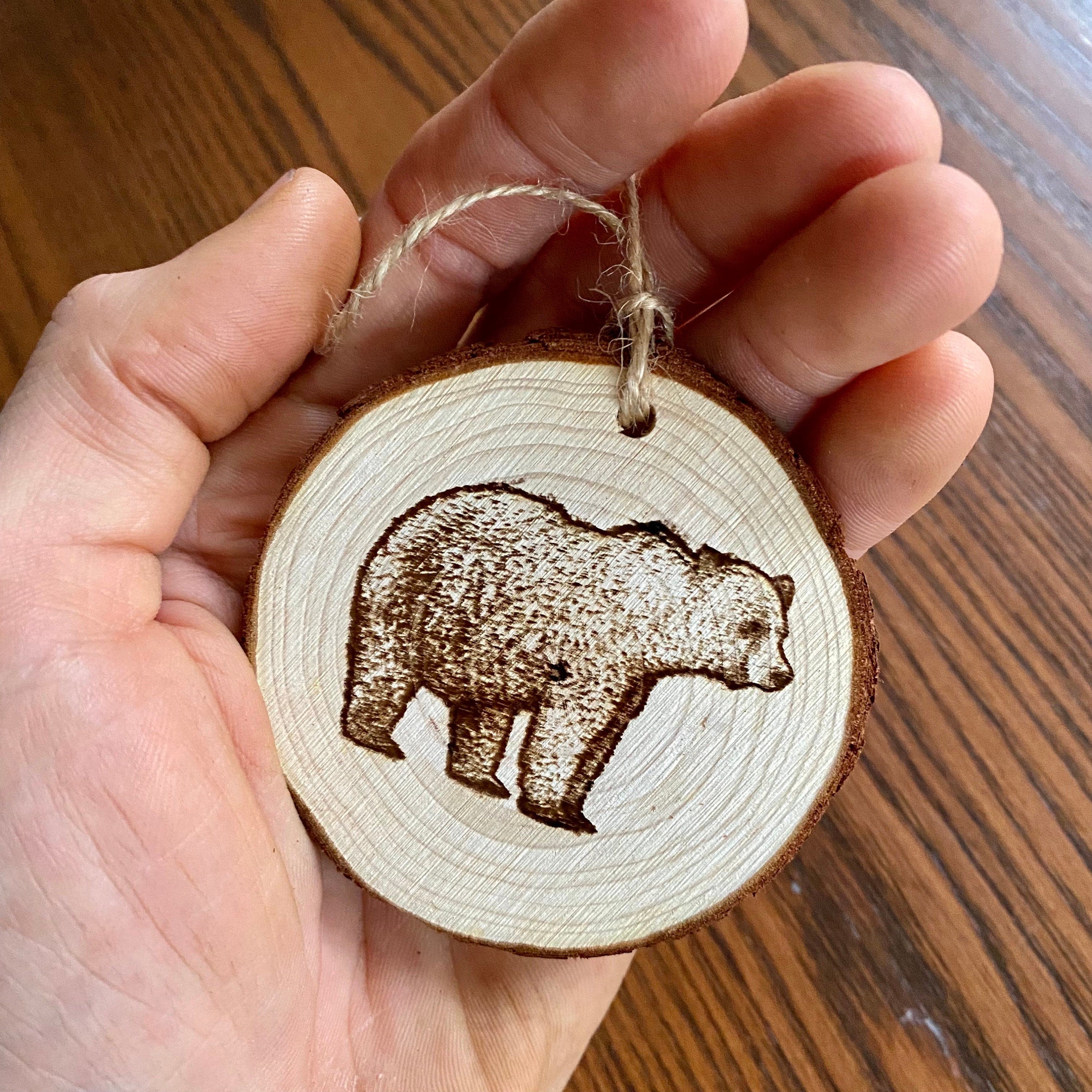 Rustic bear engraved wood slice Christmas ornament with twine, perfect for holiday decor.