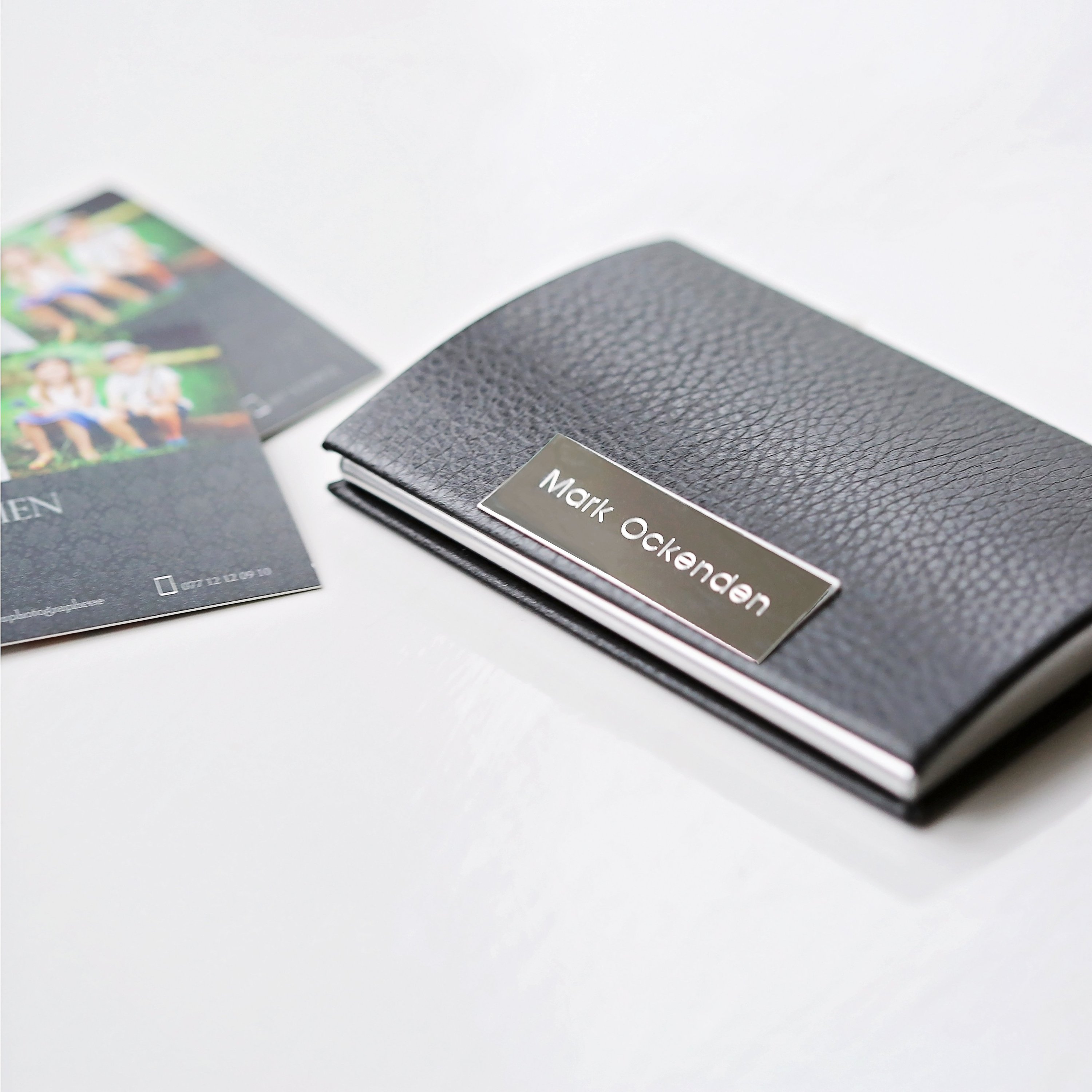 Engraved business card and credit card holder made from polished stainless steel, featuring a snap-lock magnetic closure and available in brown and black.