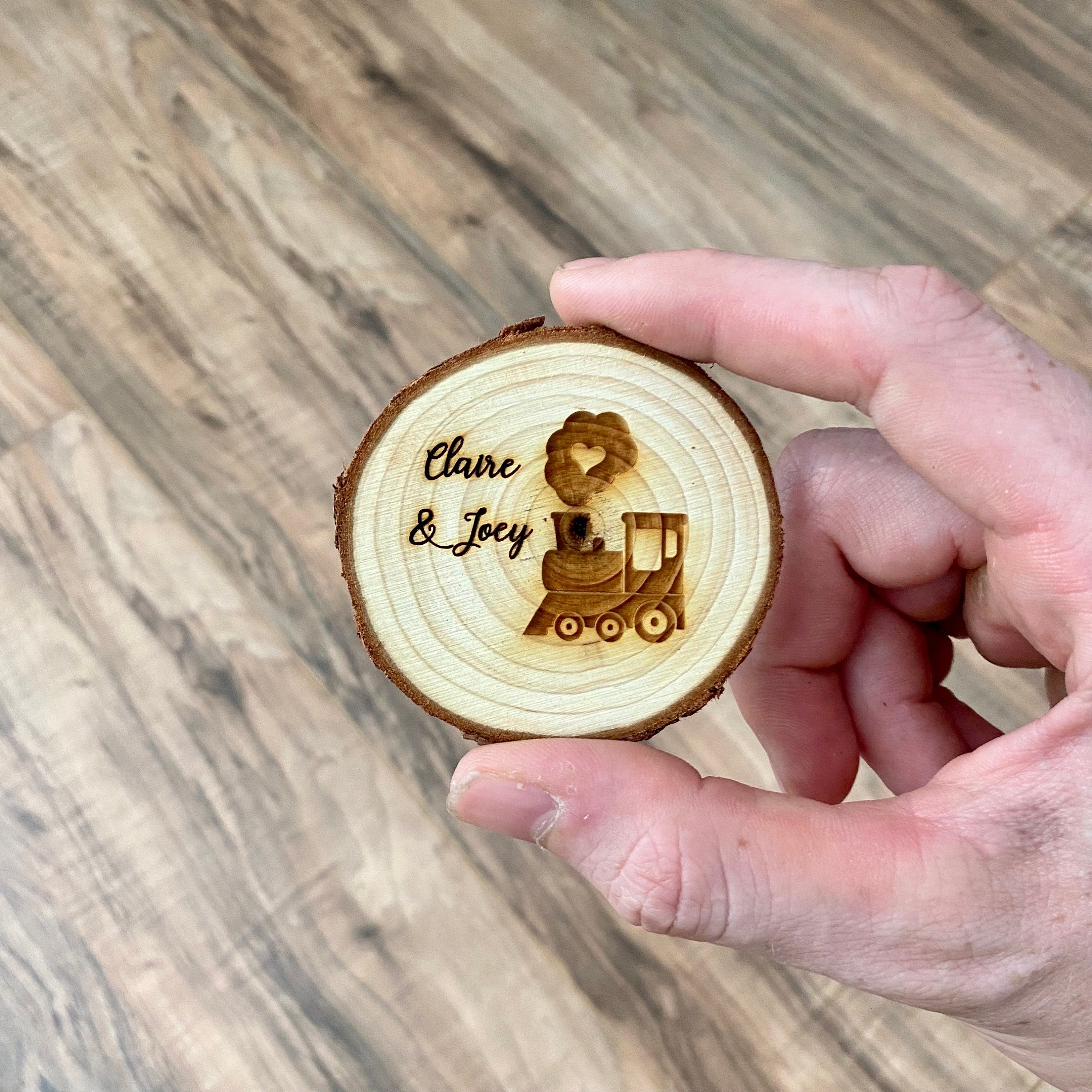 Personalized engraved wood slice birthday party favor featuring a cute train image and custom names, with a magnet on the back.