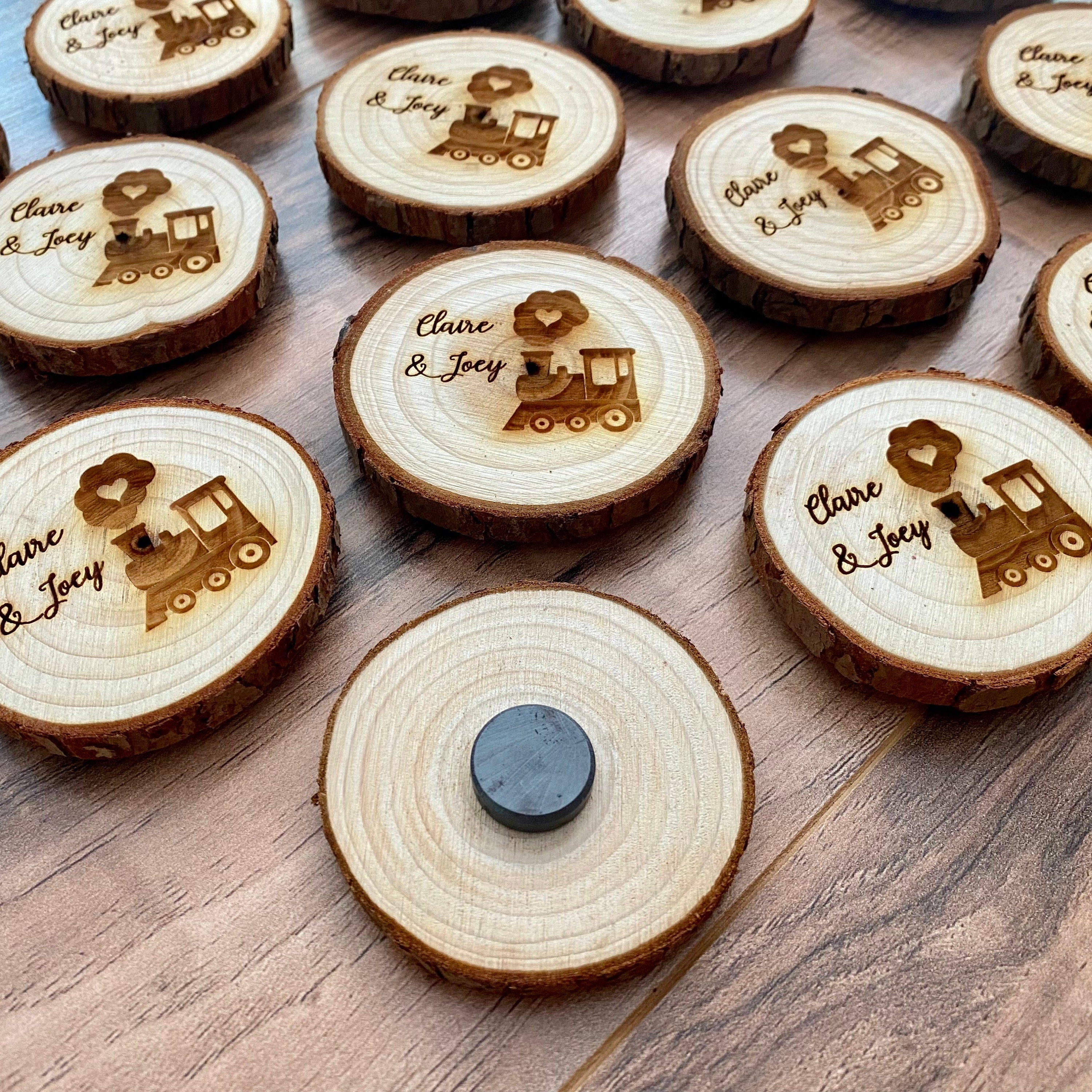 Personalized engraved wood slice birthday party favor featuring a cute train image and custom names, with a magnet on the back.