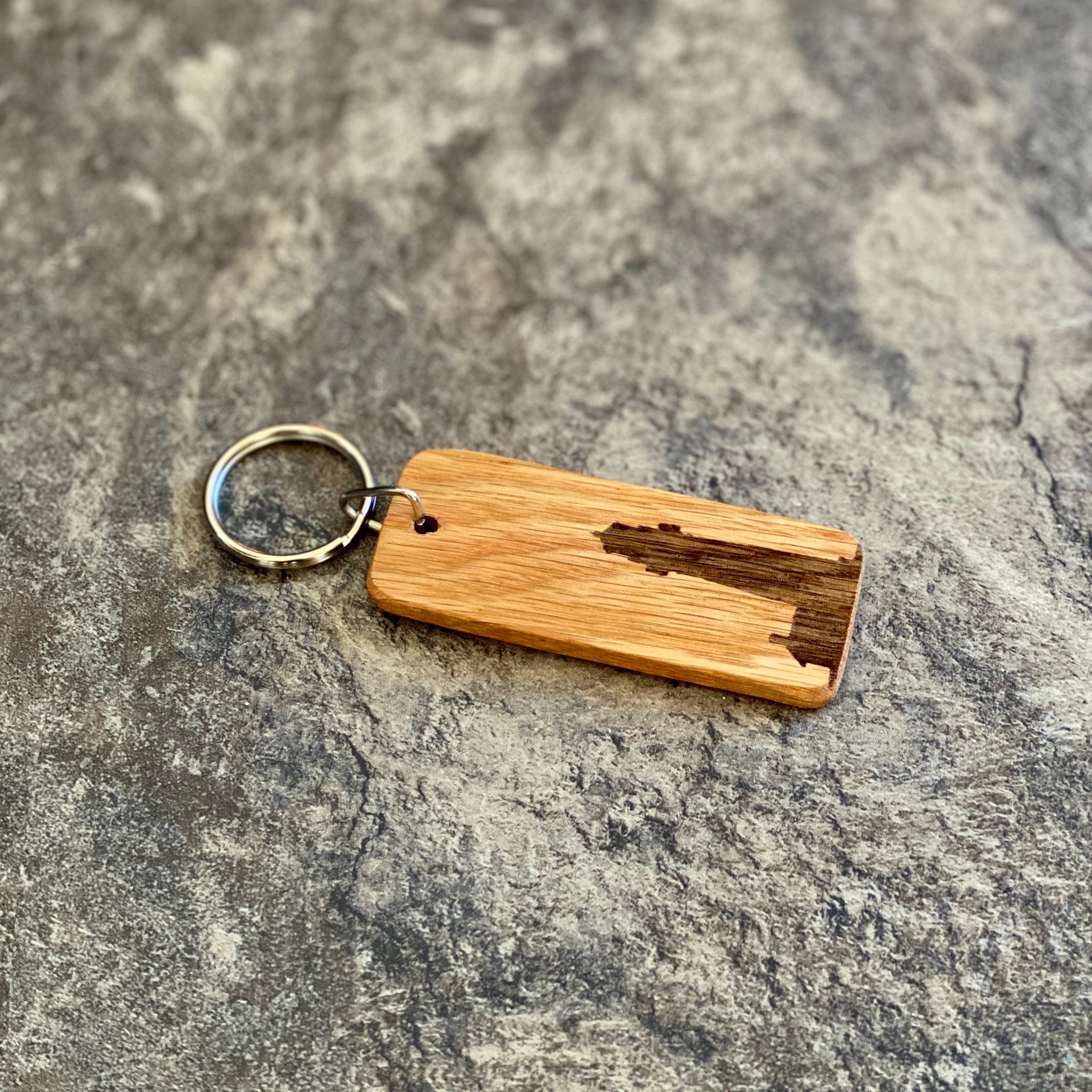 A rustic wooden keychain featuring a laser engraved lighthouse silhouette, showcasing its natural oak finish and custom engraving option.