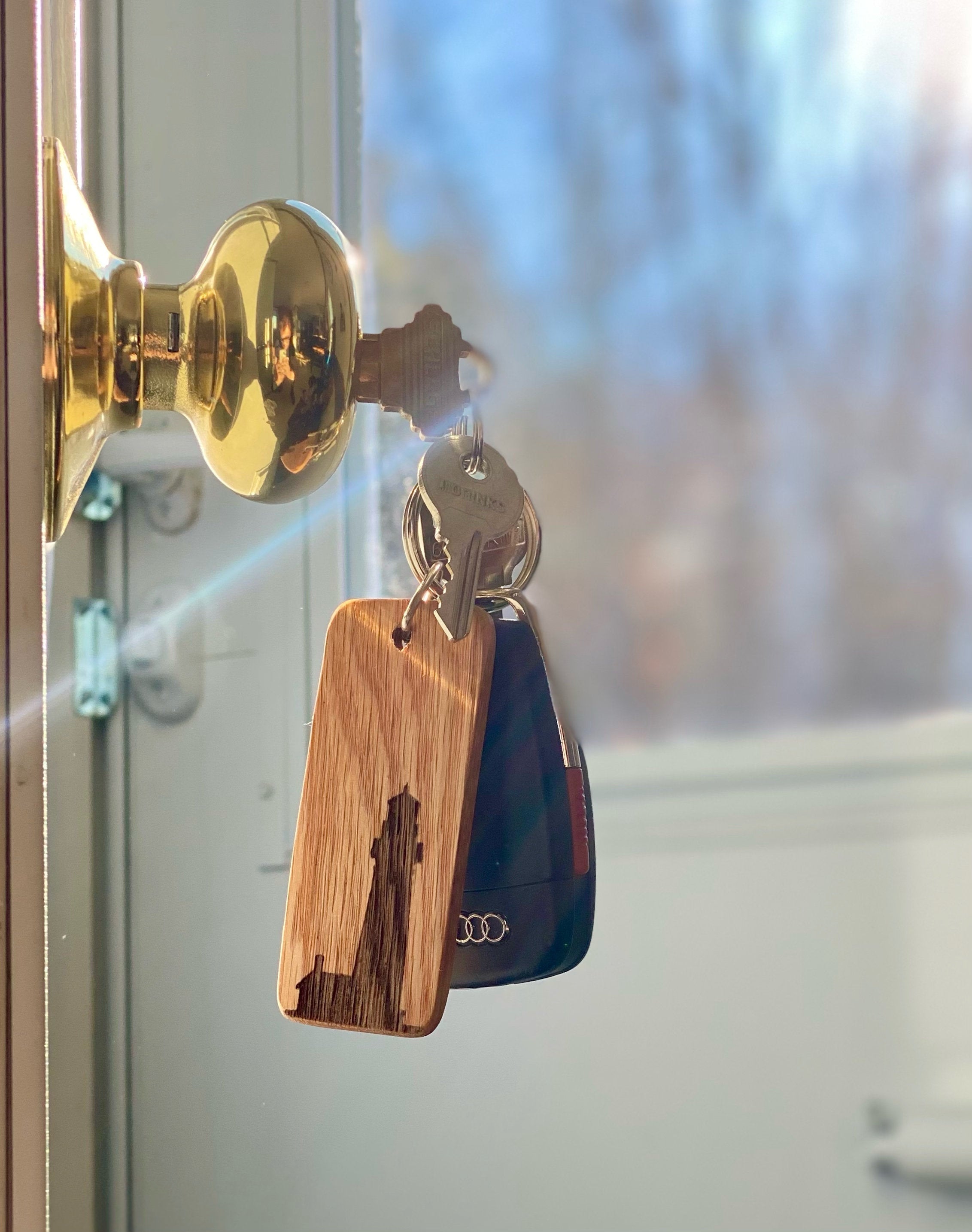 A rustic wooden keychain featuring a laser engraved lighthouse silhouette, showcasing its natural oak finish and custom engraving option.
