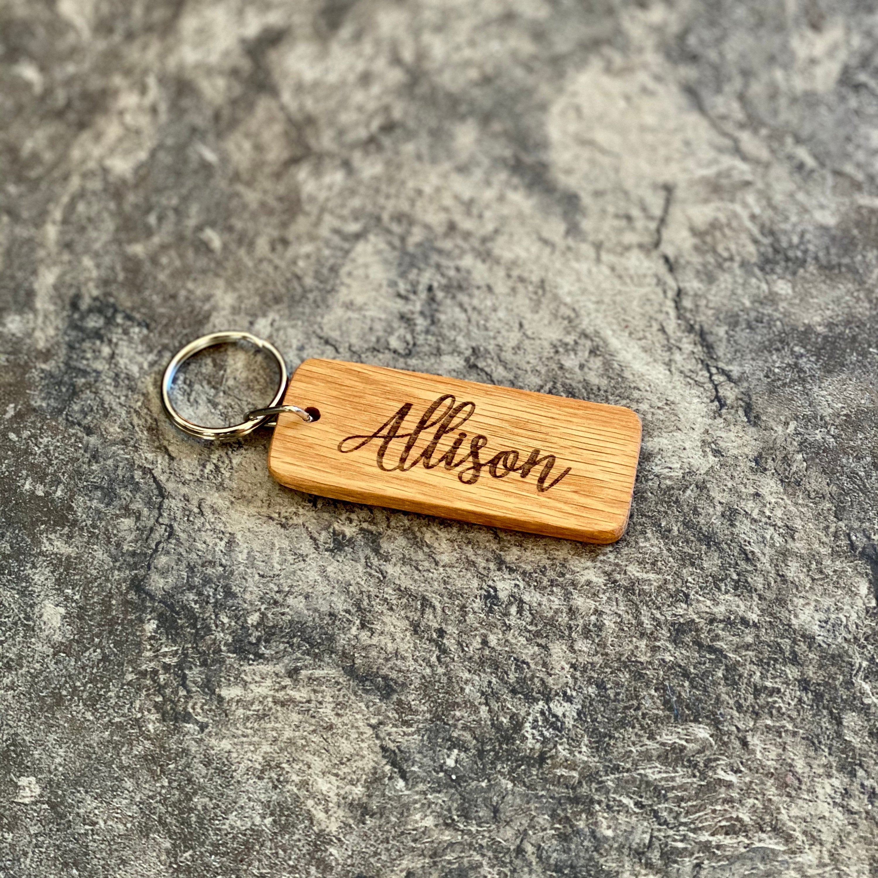 A rustic wooden keychain featuring a laser engraved lighthouse silhouette, showcasing its natural oak finish and custom engraving option.