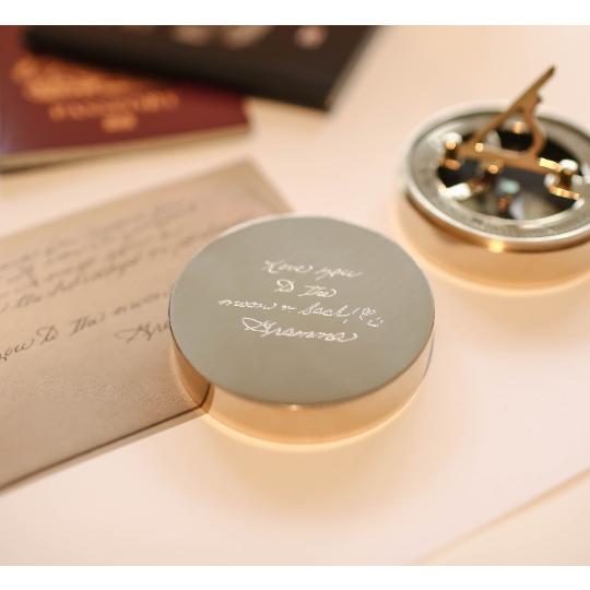 Personalised brass nautical sundial compass with custom handwriting engraving, complete with protective pouch and gift box.