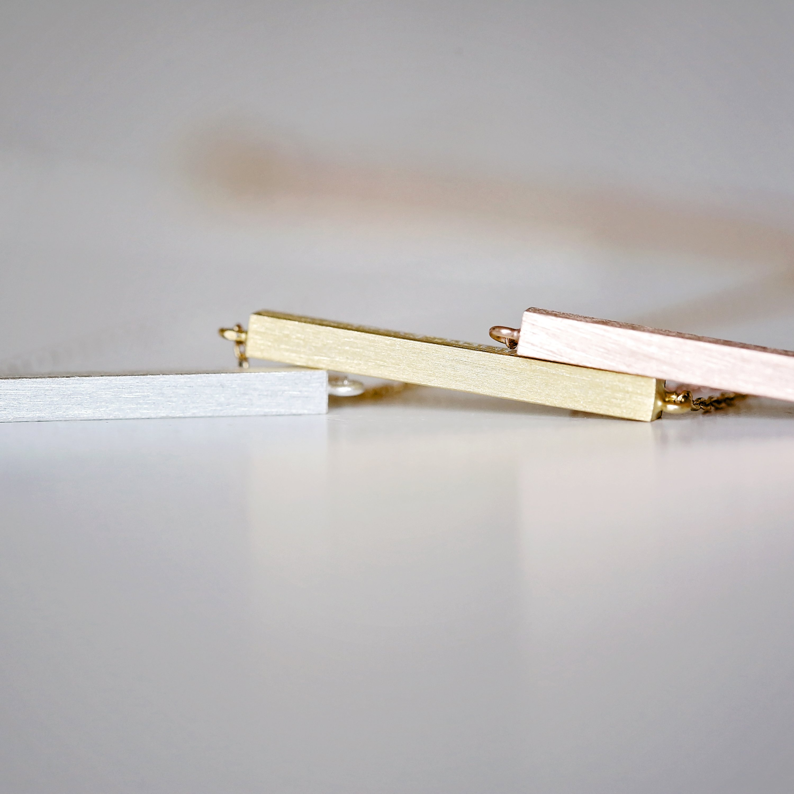 A stunning personalised horizontal necklace in silver, gold, and rose gold, featuring custom engraving options and an adjustable chain.