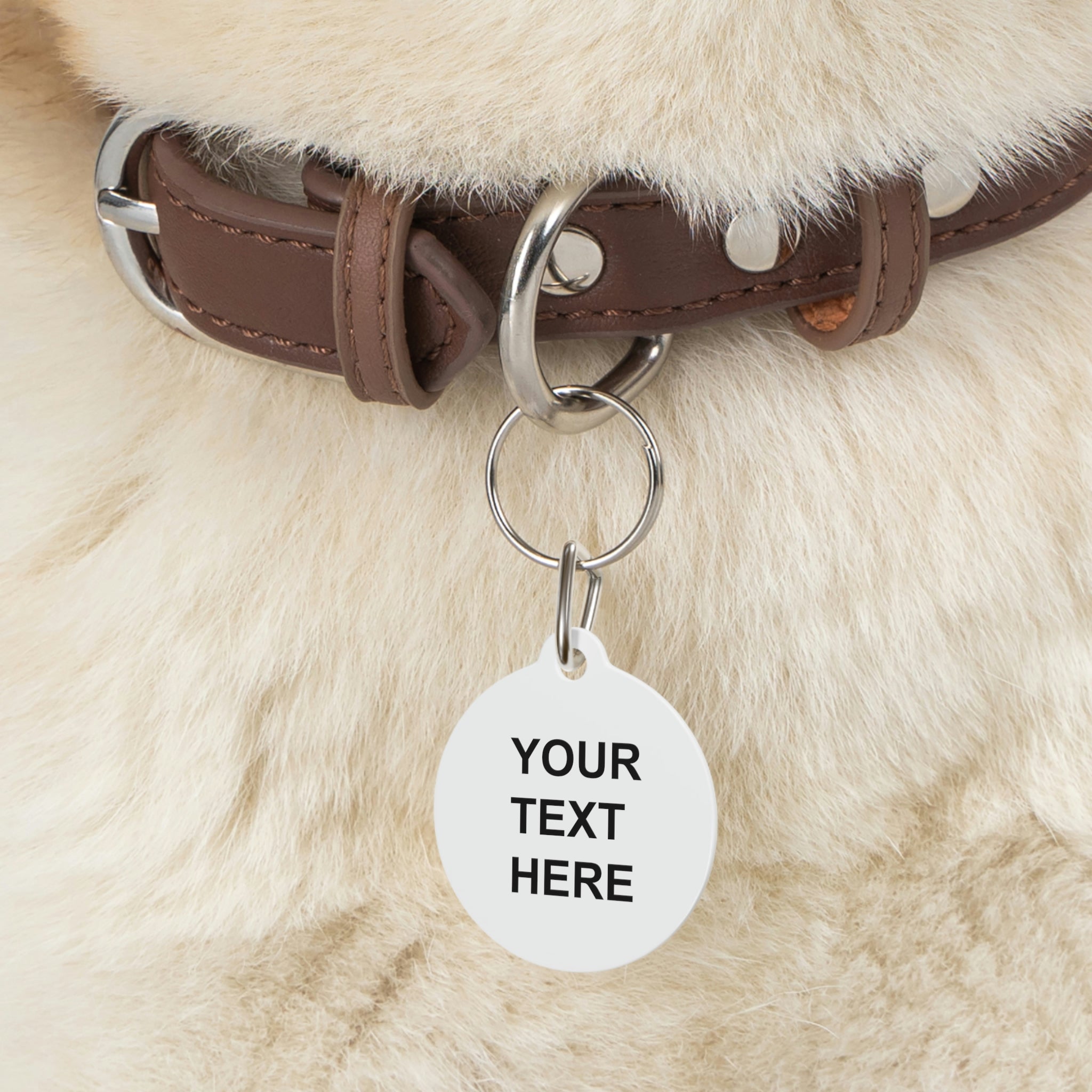A personalized pet tag made of white coated metal, featuring custom text on both sides, attached with a sturdy metal clip.