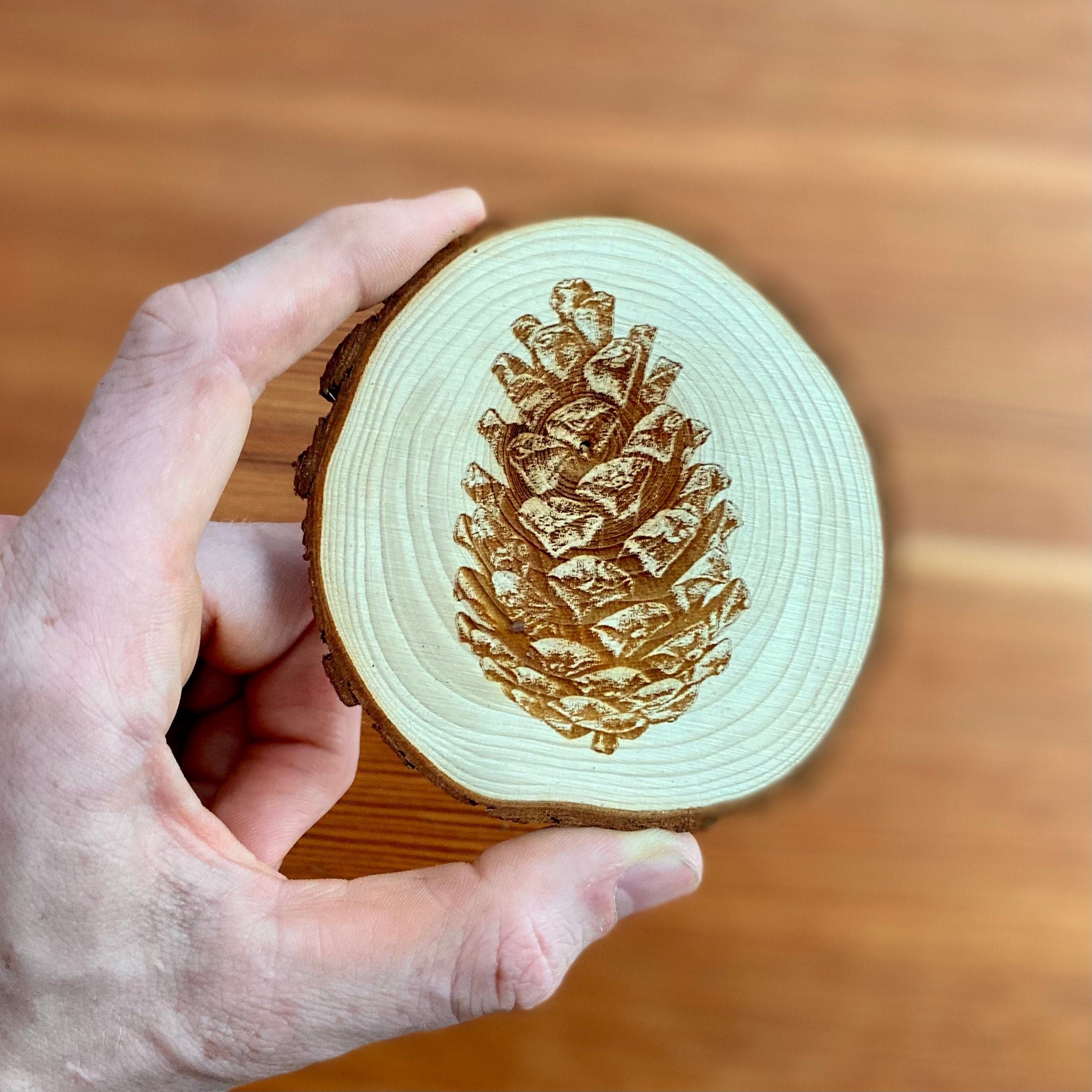 A set of four pine cone engraved wood coasters, showcasing intricate designs on a natural wood surface, ideal for home decor.