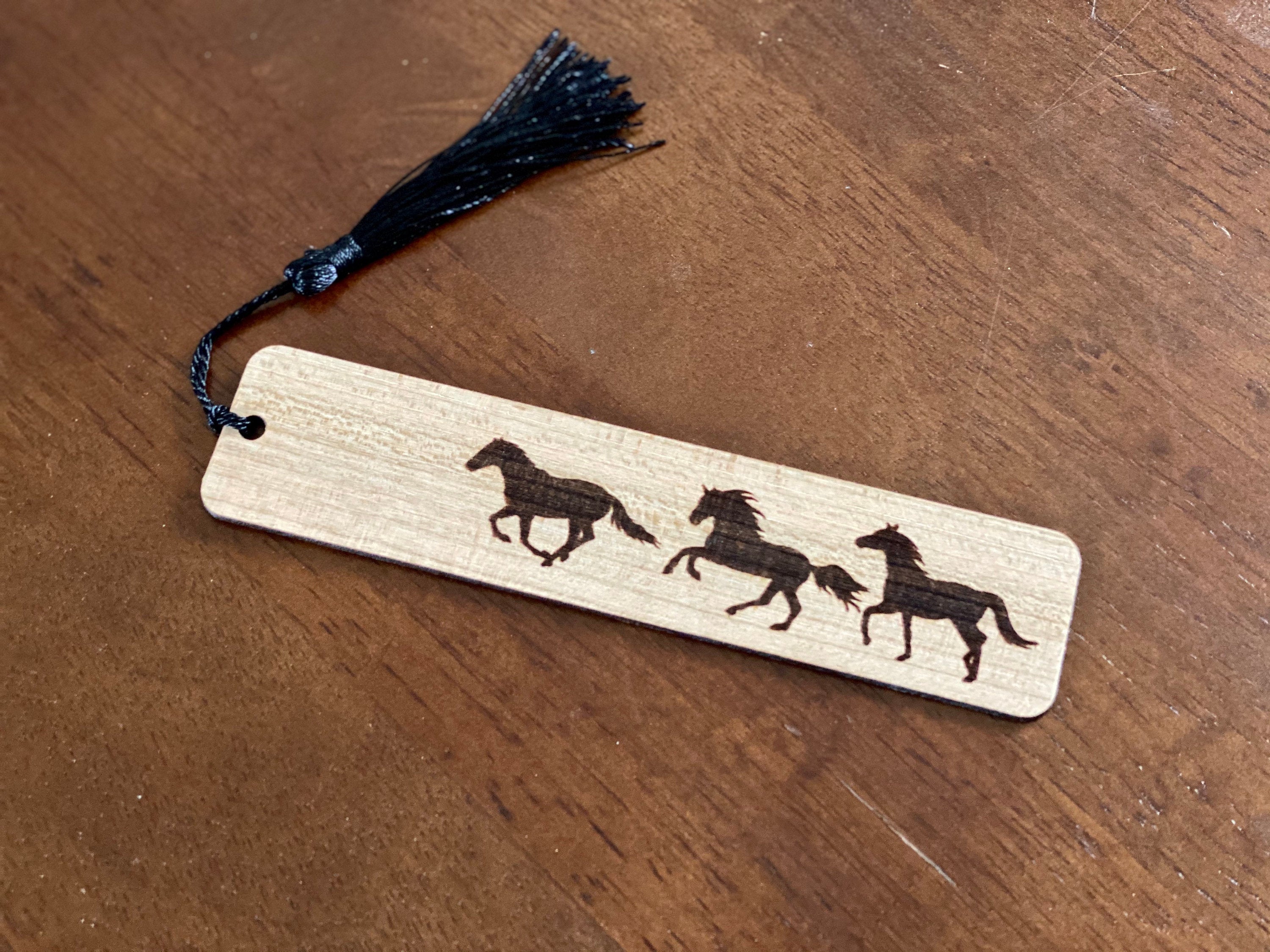 Engraved wood bookmark featuring galloping horses, made of cherry hardwood with a colorful tassel.