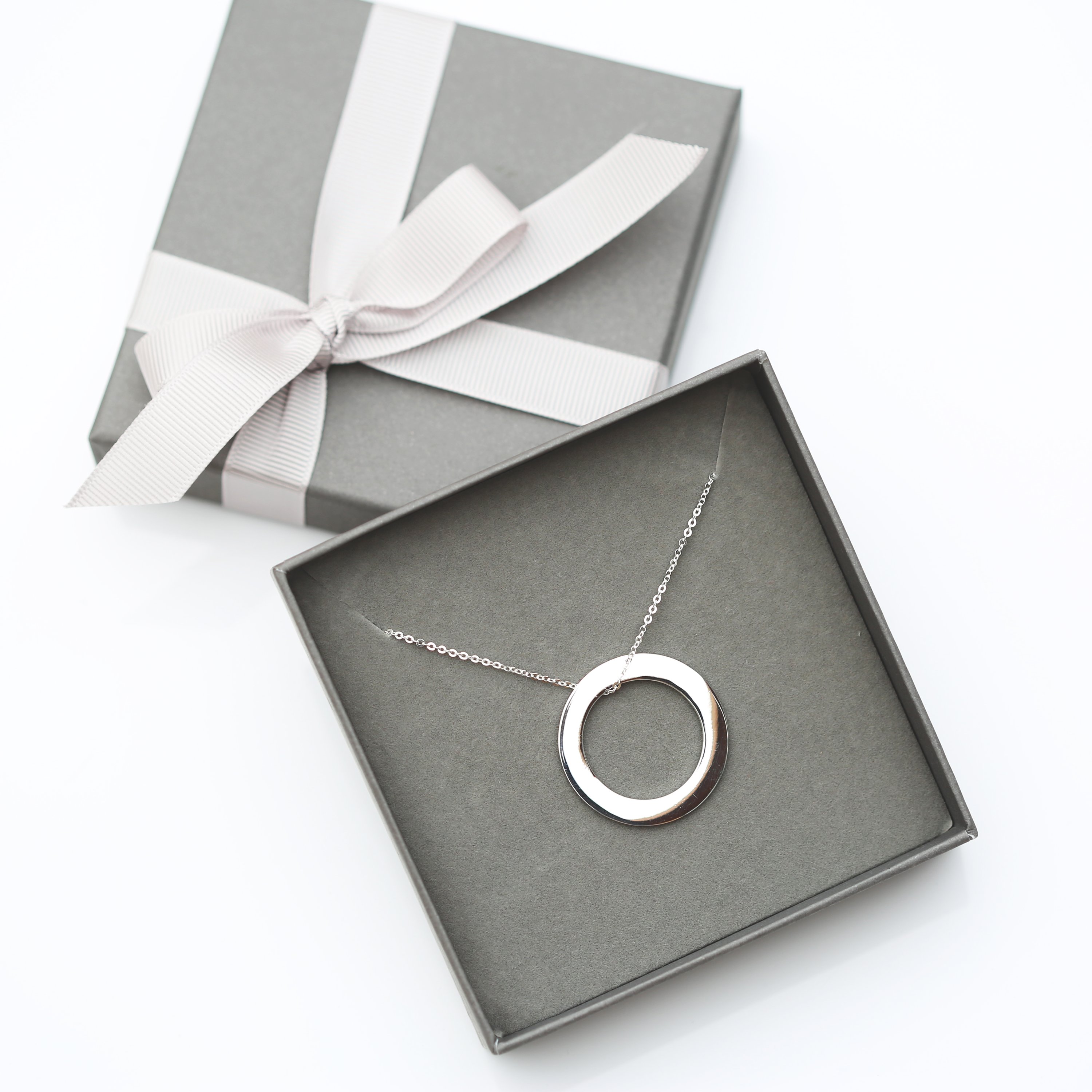 A stunning sterling silver halo necklace with an engraved pendant, elegantly displayed in a gift box.