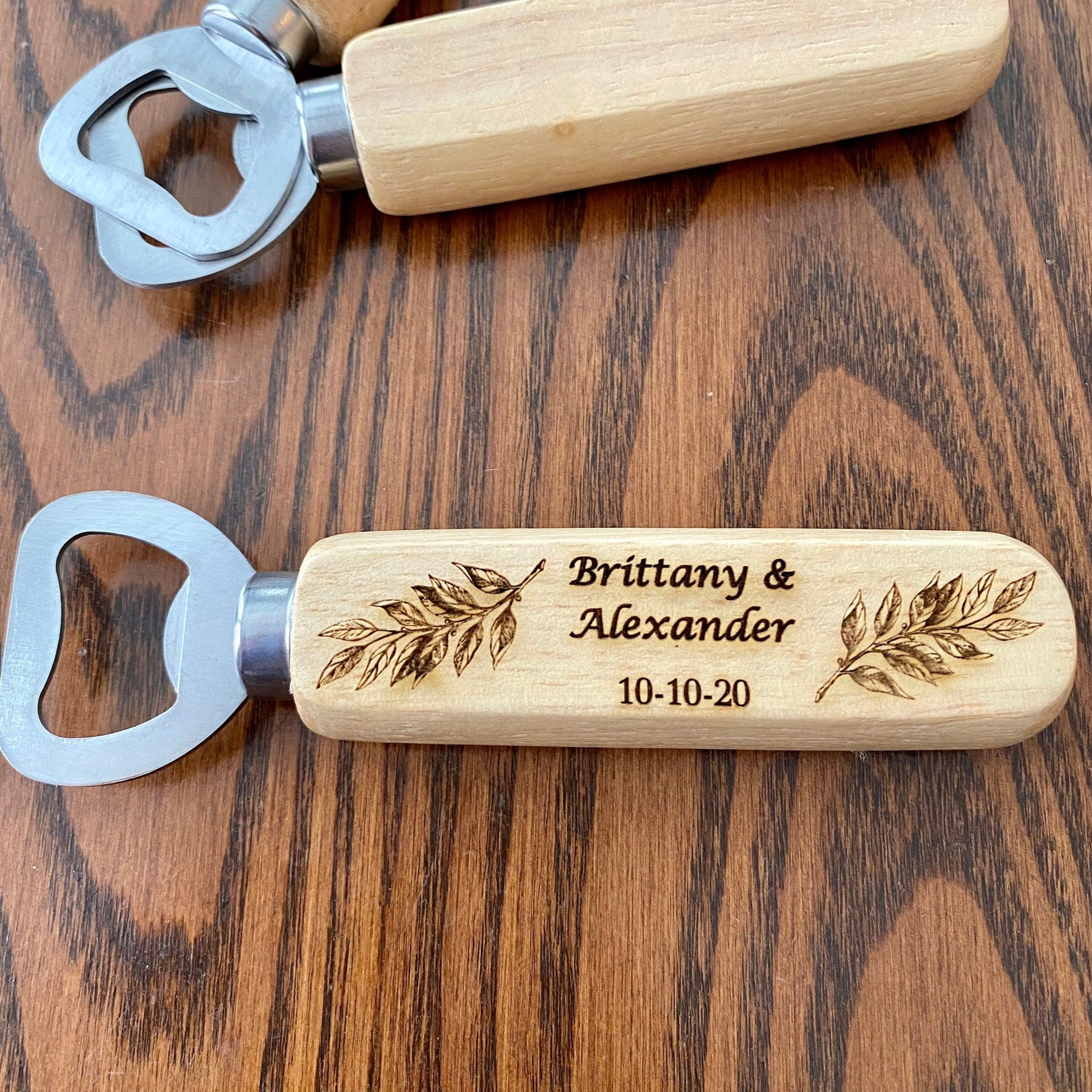 Personalized wooden bottle opener with engraved names and leaf design, perfect for rustic wedding favors.