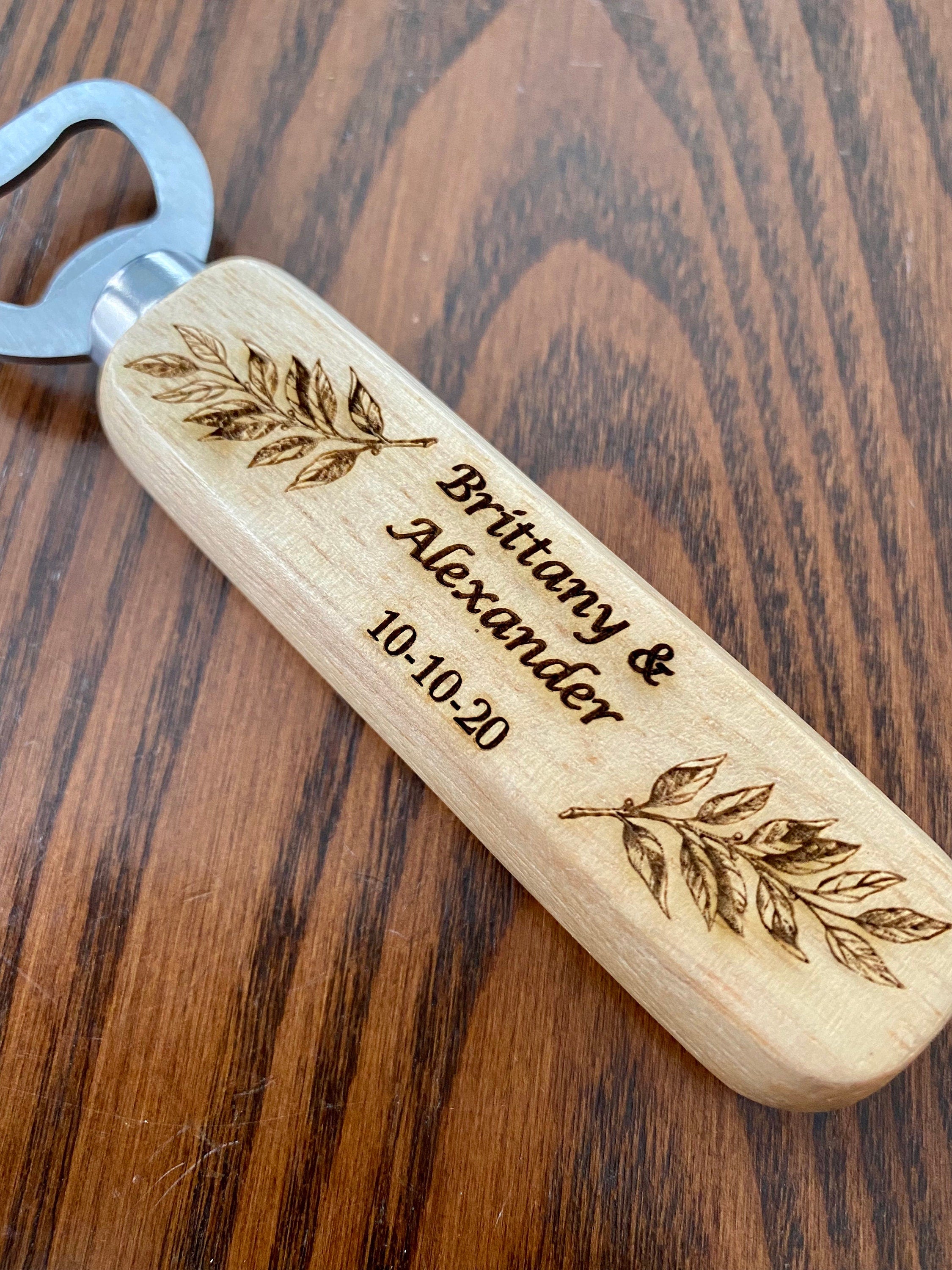 Personalized wooden bottle opener with engraved names and leaf design, perfect for rustic wedding favors.