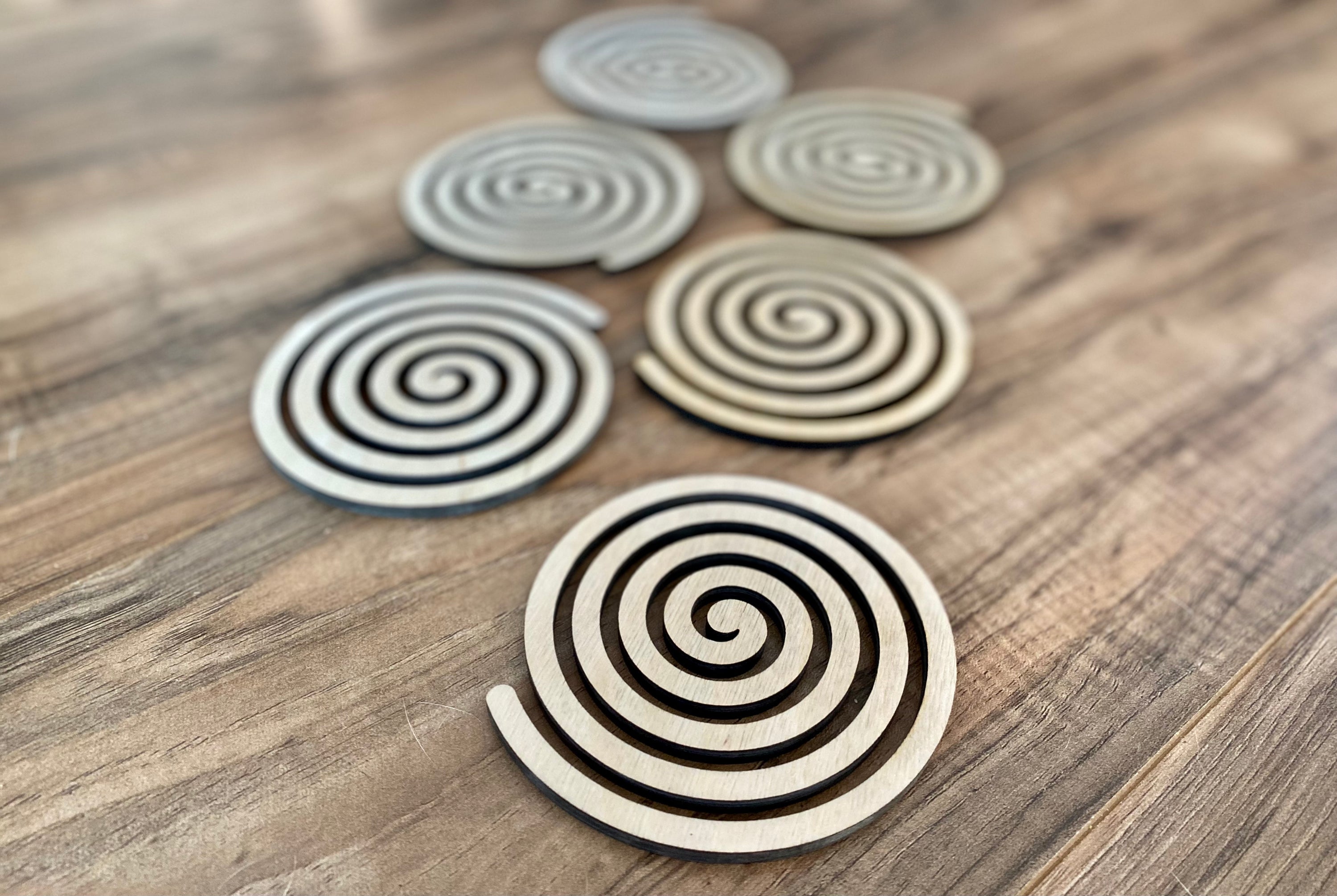 Set of unique wood spiral coasters made from high-quality birch plywood, showcasing a beautiful spiral design.