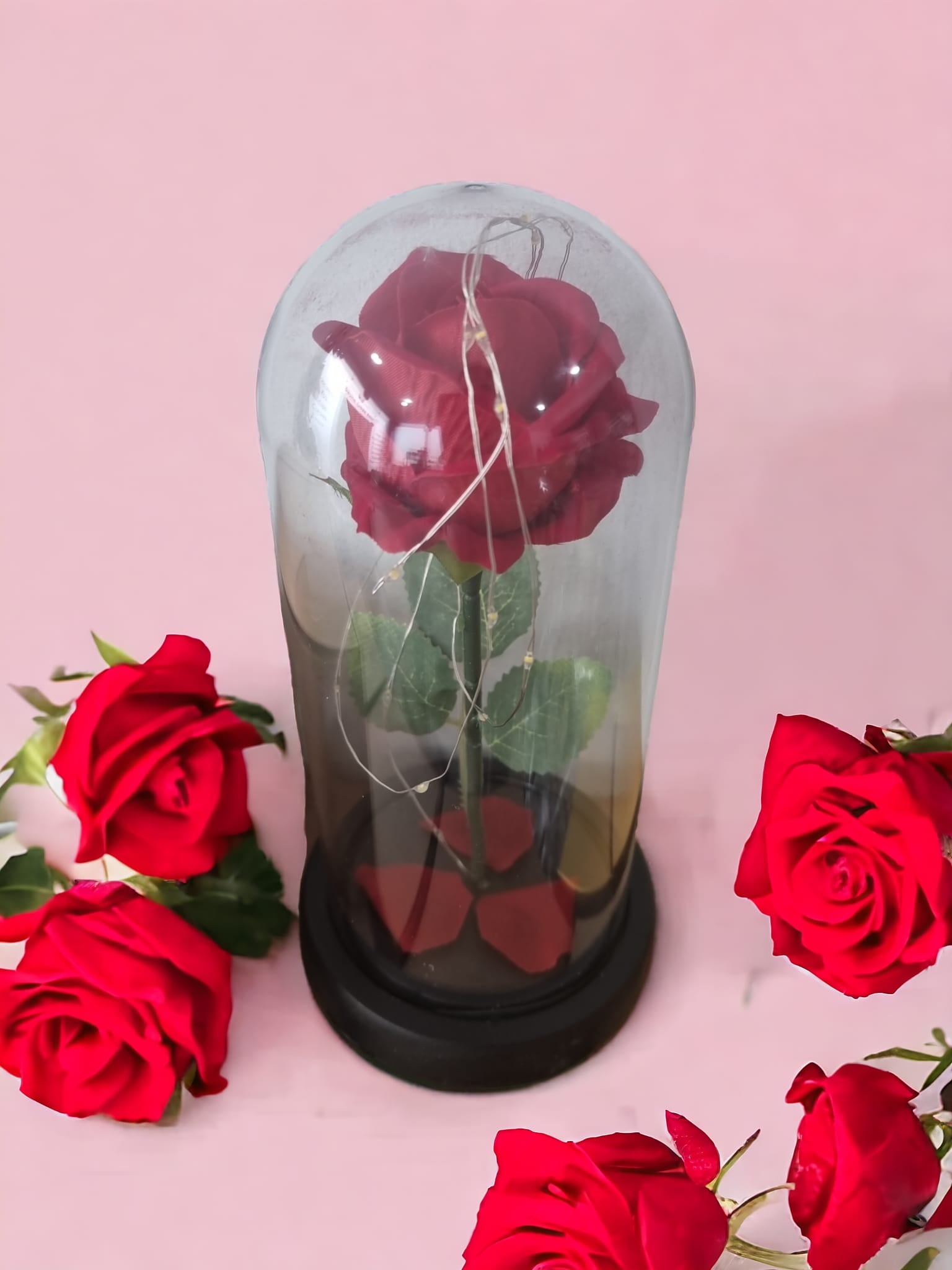 A stunning red rose encased in a glass acrylic cylinder, illuminated by soft twinkling lights, symbolizing love and romance.