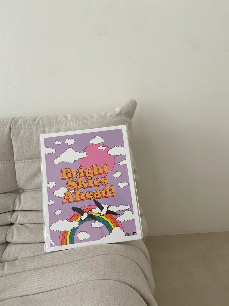 A vibrant printed poster titled 'Bright Skies Ahead' featuring uplifting imagery, designed by Ashley Molesso.