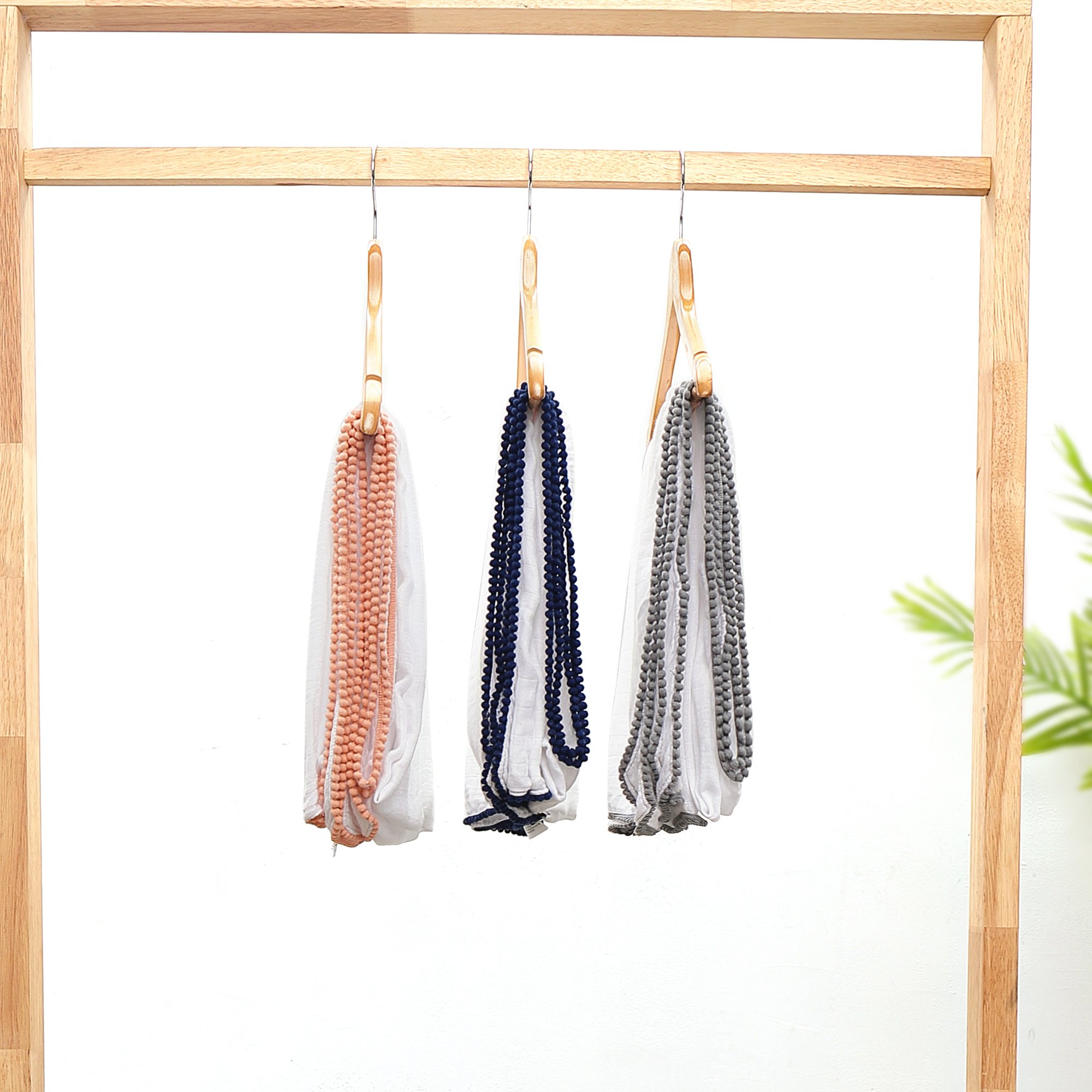 A soft bamboo and cotton swaddle featuring playful pom pom trim, perfect for newborns to toddlers.