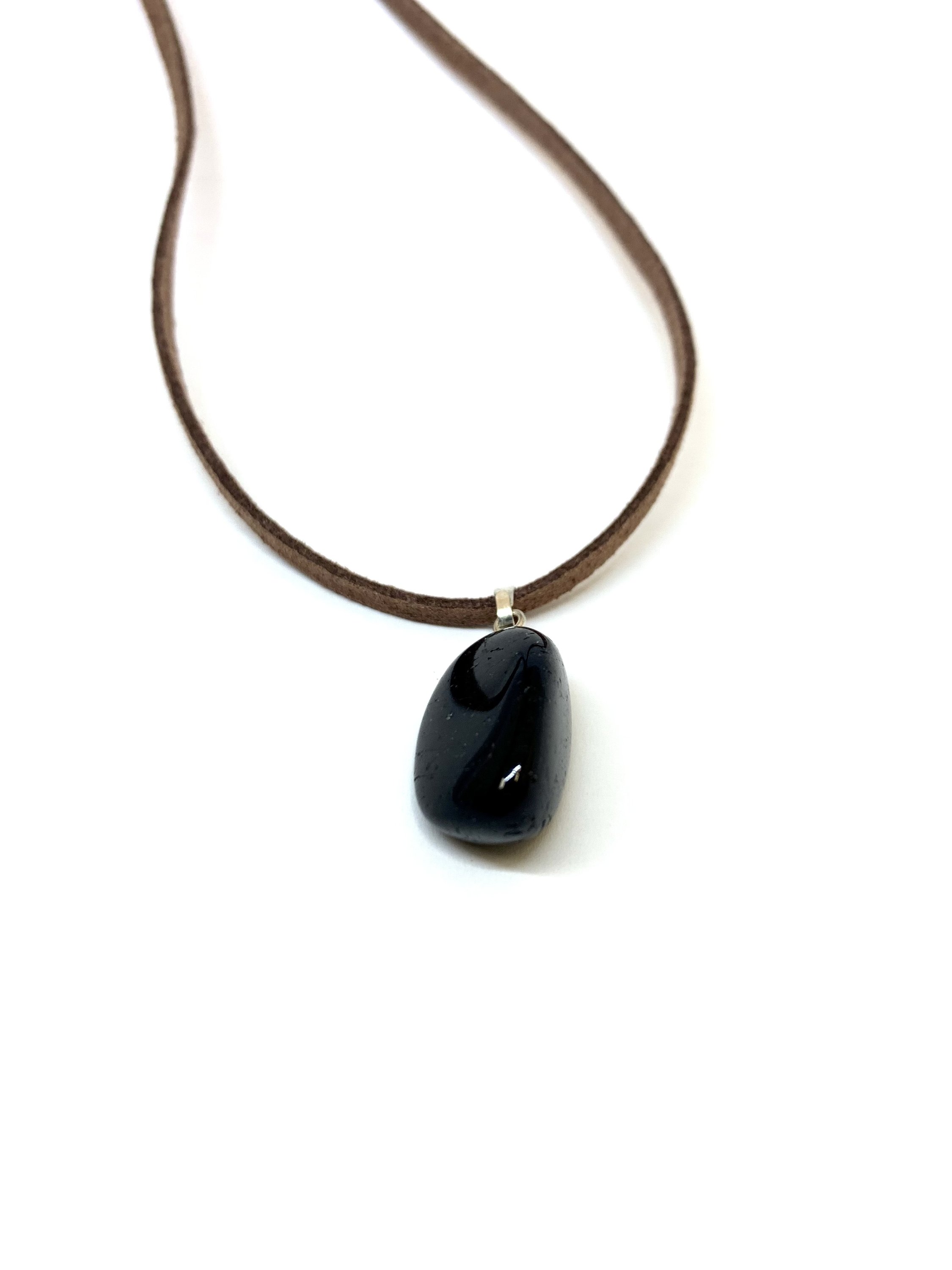 Black Tourmaline Tumbled Pendant on a tan suede necklace, showcasing its natural beauty and protective qualities.