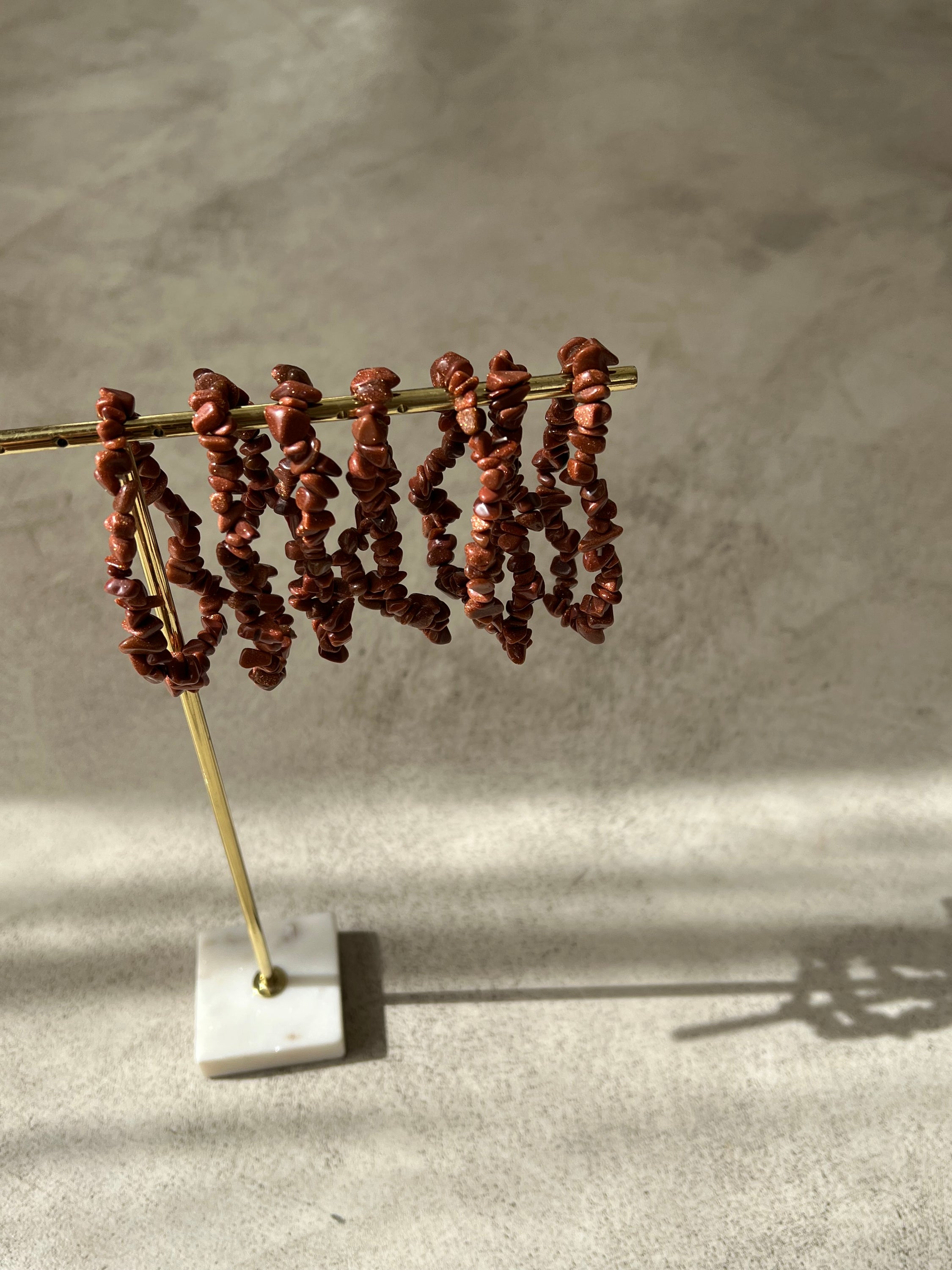 Bracelet en pierre de soleil avec paillettes de cuivre, symbolisant la joie et la vitalité, sur fond neutre.