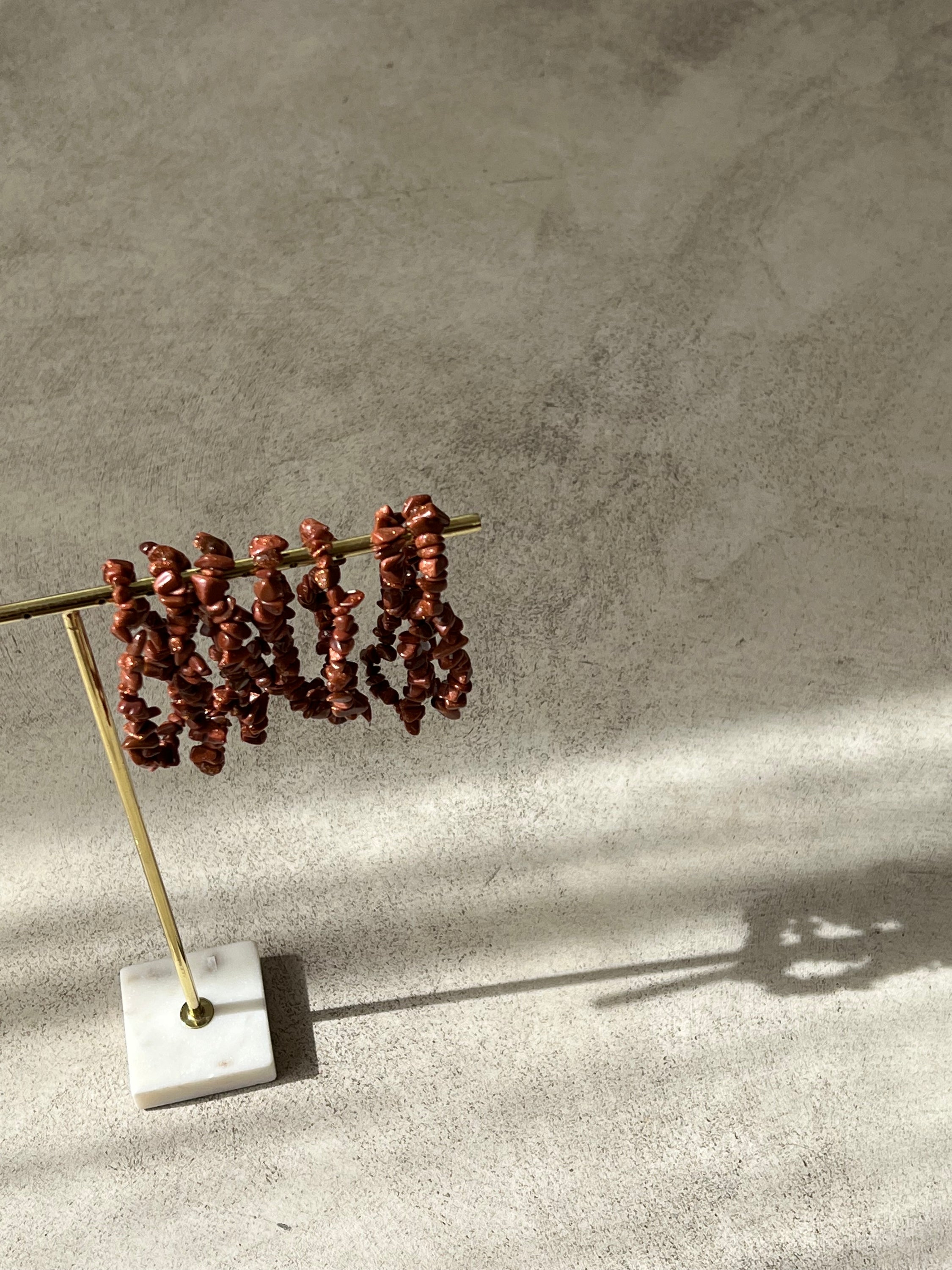 Bracelet en pierre de soleil avec paillettes de cuivre, symbolisant la joie et la vitalité, sur fond neutre.