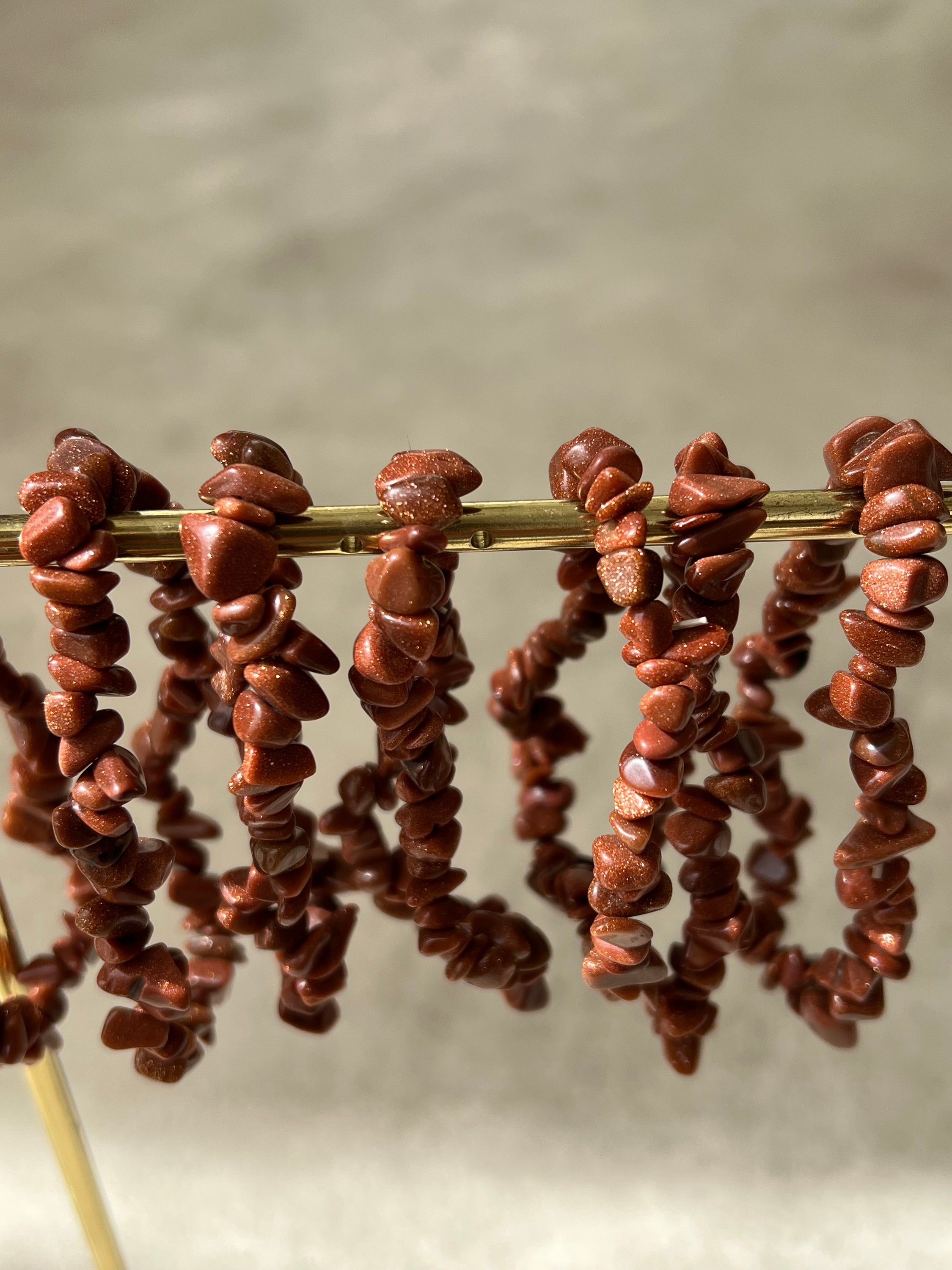 Bracelet en pierre de soleil avec paillettes de cuivre, symbolisant la joie et la vitalité, sur fond neutre.