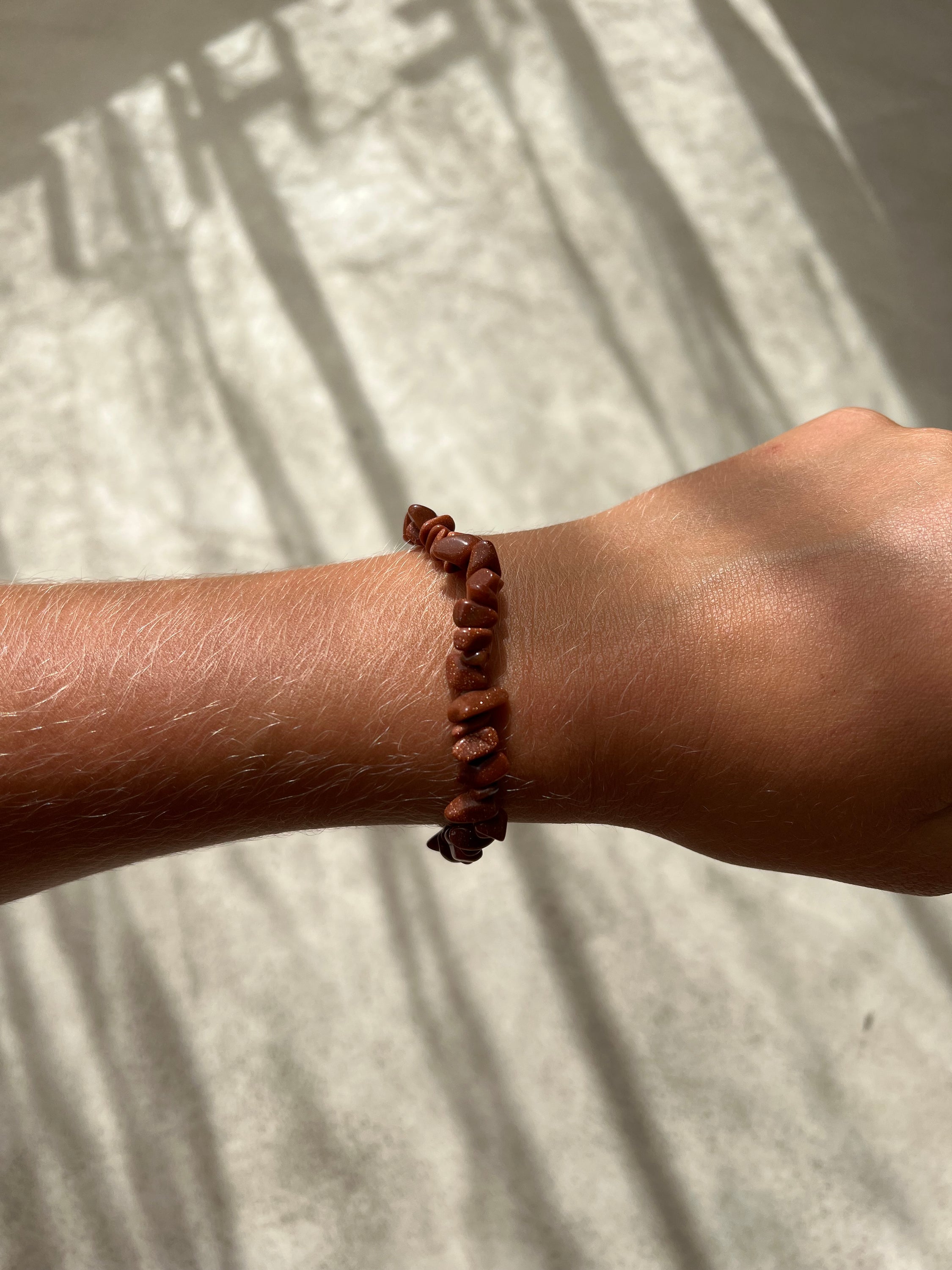 Bracelet en pierre de soleil avec paillettes de cuivre, symbolisant la joie et la vitalité, sur fond neutre.