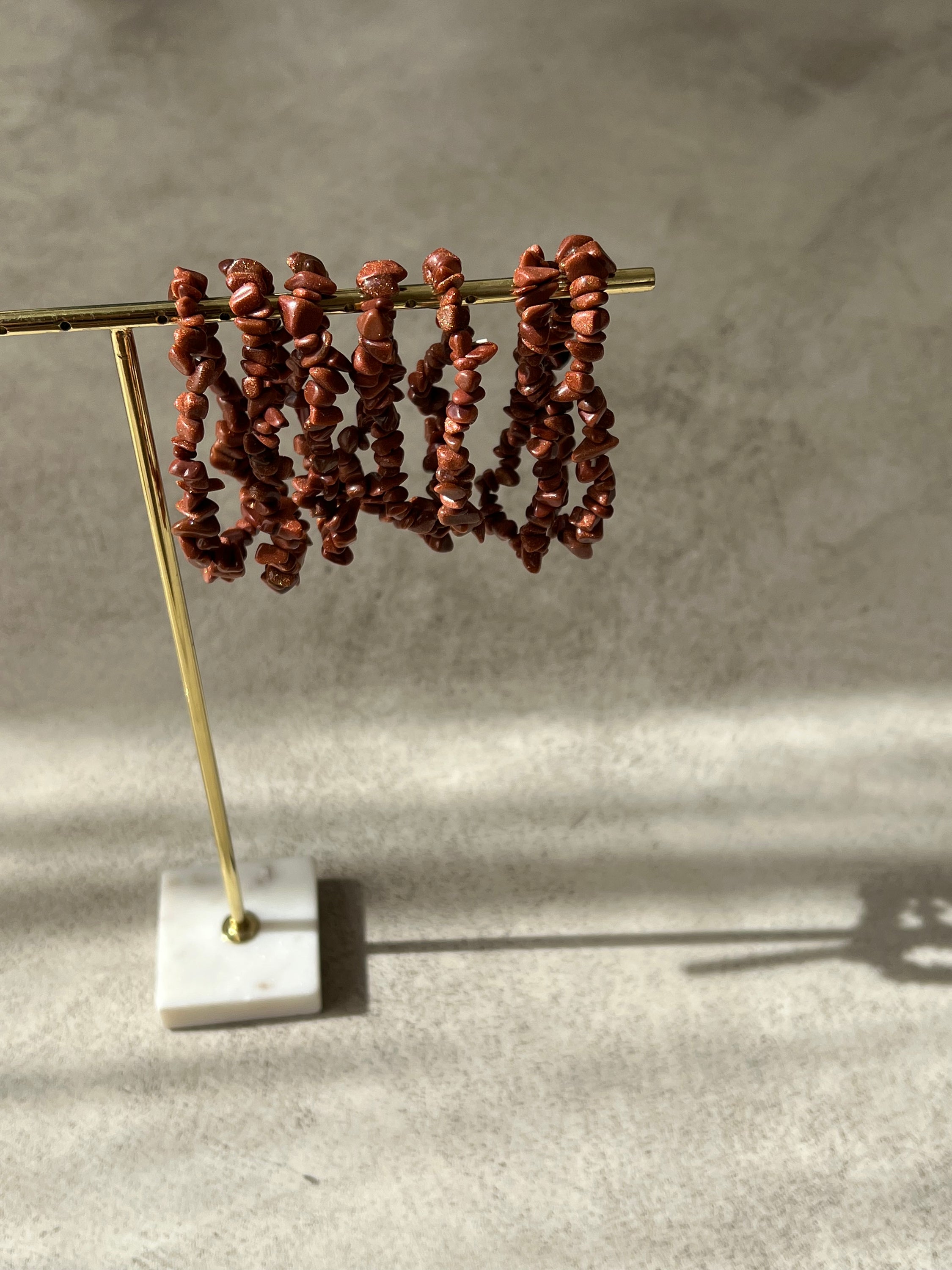 Bracelet en pierre de soleil avec paillettes de cuivre, symbolisant la joie et la vitalité, sur fond neutre.