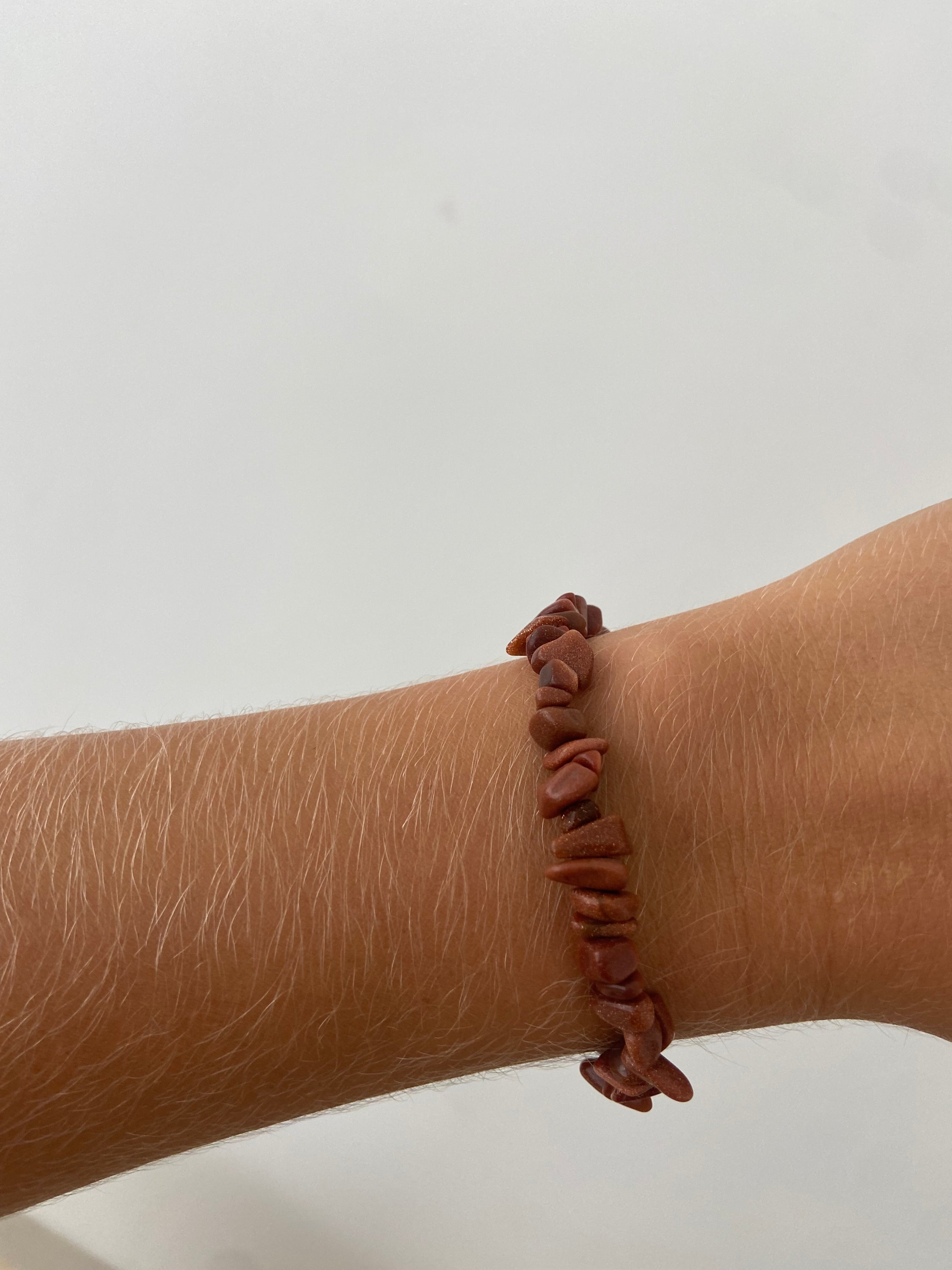 Bracelet en pierre de soleil avec paillettes de cuivre, symbolisant la joie et la vitalité, sur fond neutre.