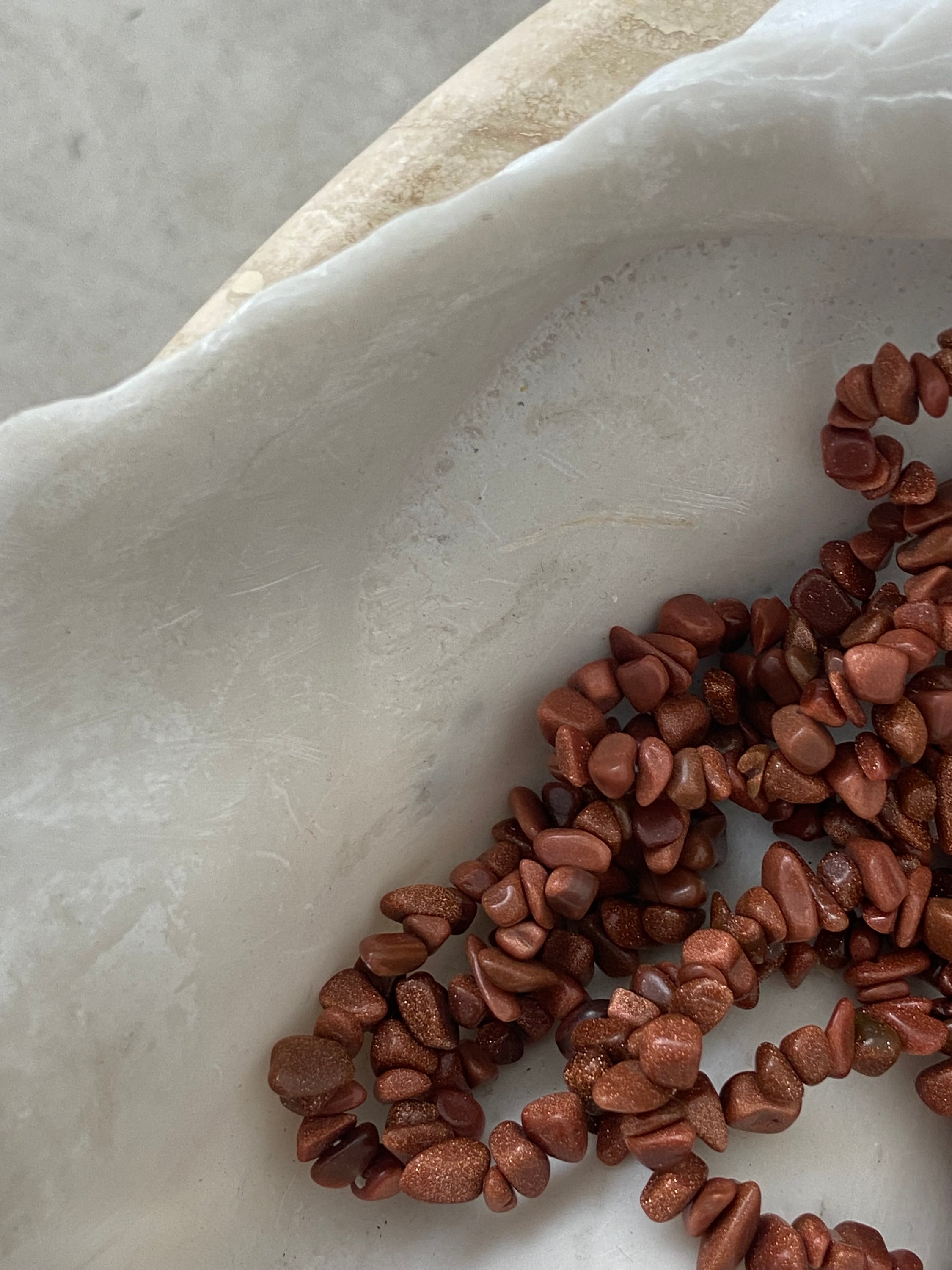 Bracelet en pierre de soleil avec paillettes de cuivre, symbolisant la joie et la vitalité, sur fond neutre.