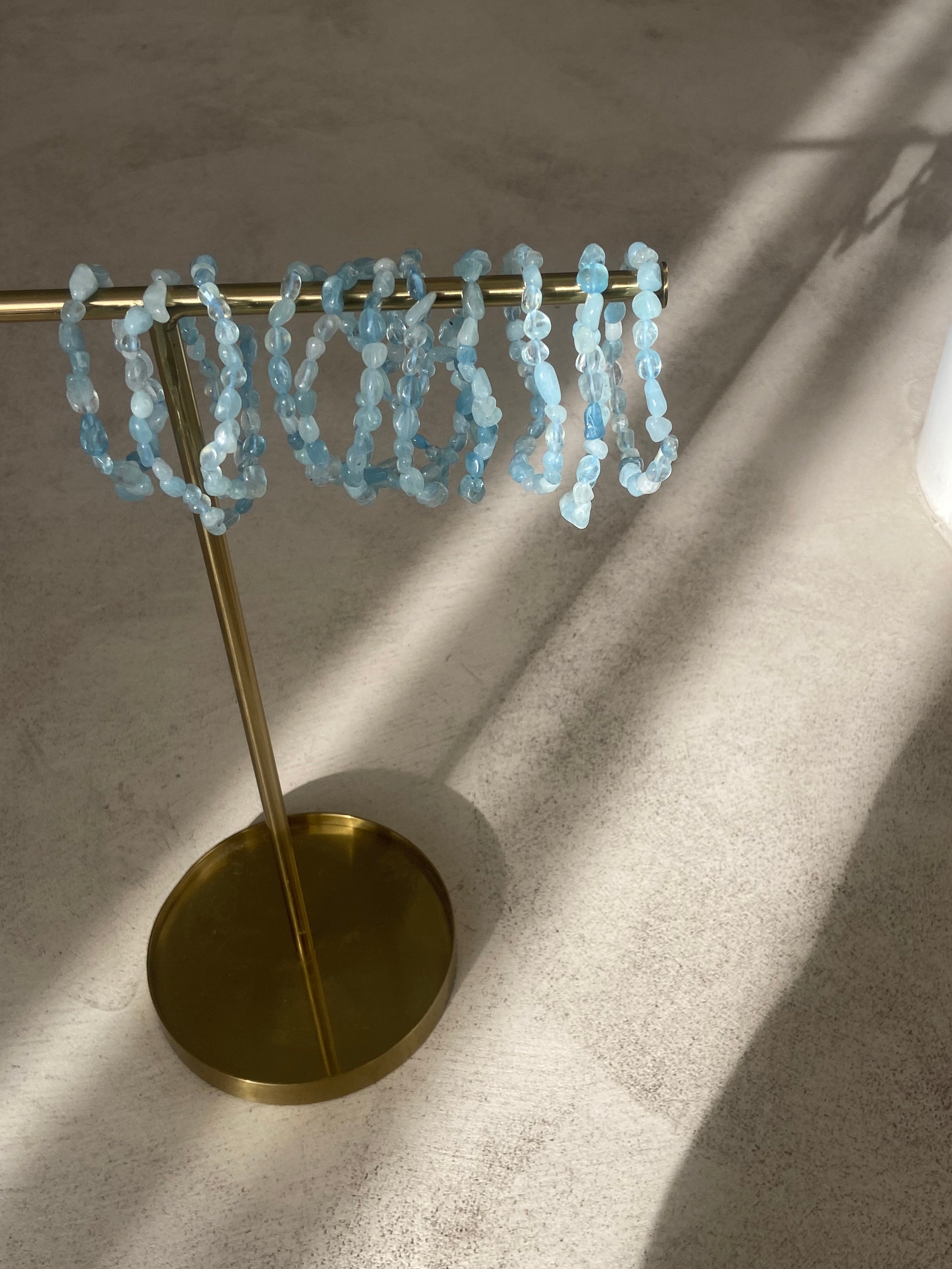 Bracelet galets en aigue marine, symbole de confiance en soi et d'équilibre énergétique, présenté sur un fond neutre.