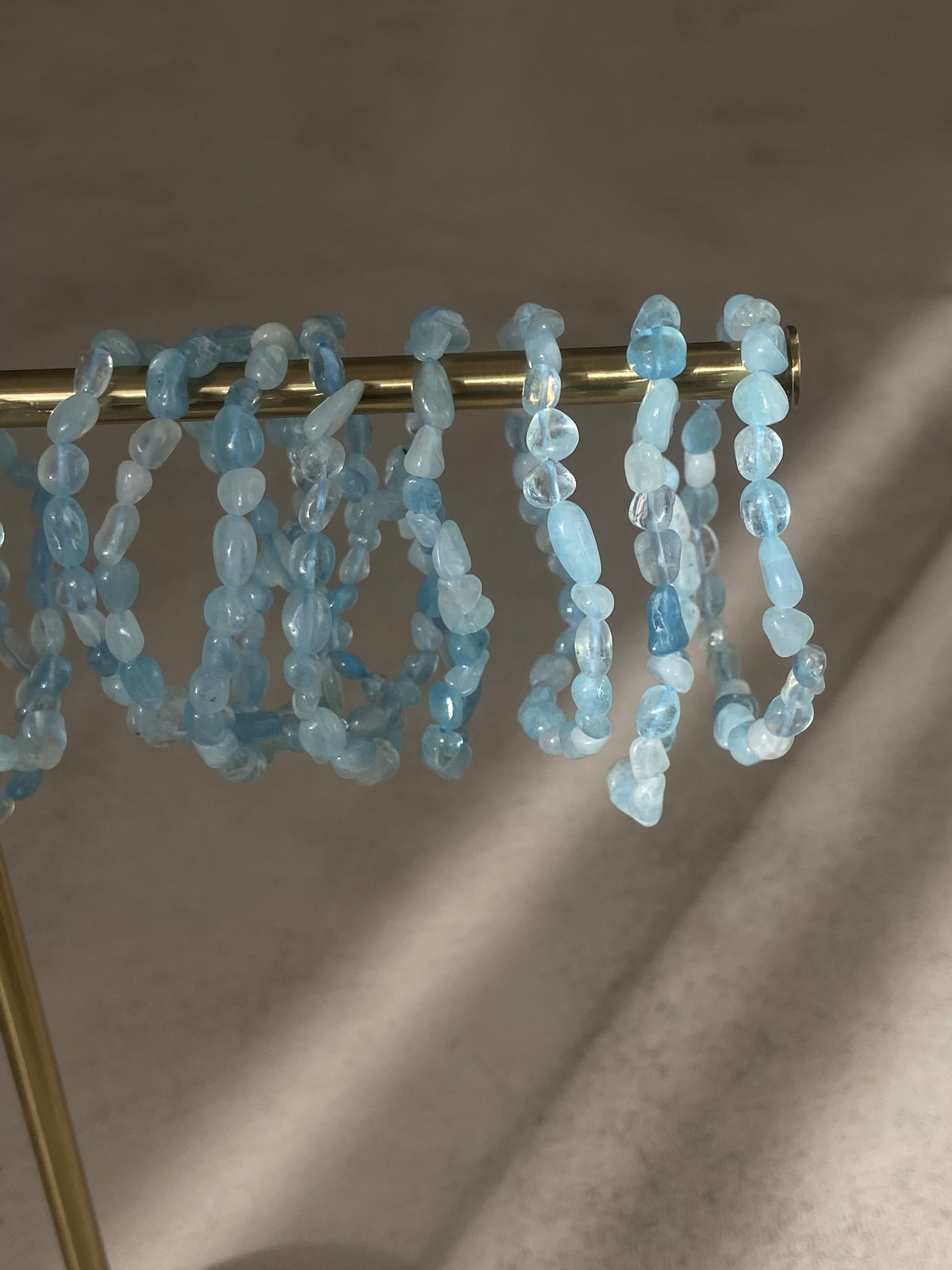 Bracelet galets en aigue marine, symbole de confiance en soi et d'équilibre énergétique, présenté sur un fond neutre.