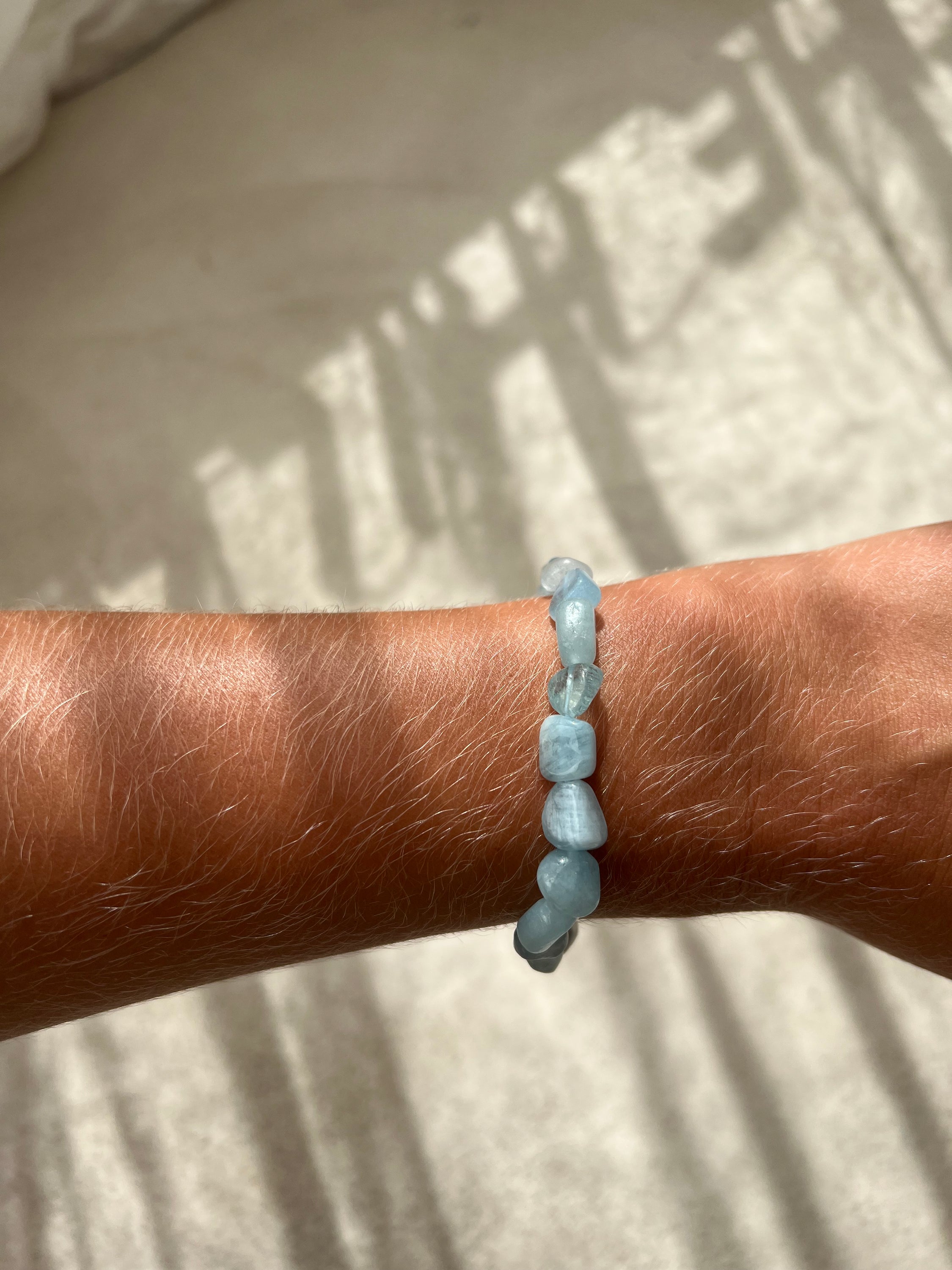 Bracelet galets en aigue marine, symbole de confiance en soi et d'équilibre énergétique, présenté sur un fond neutre.